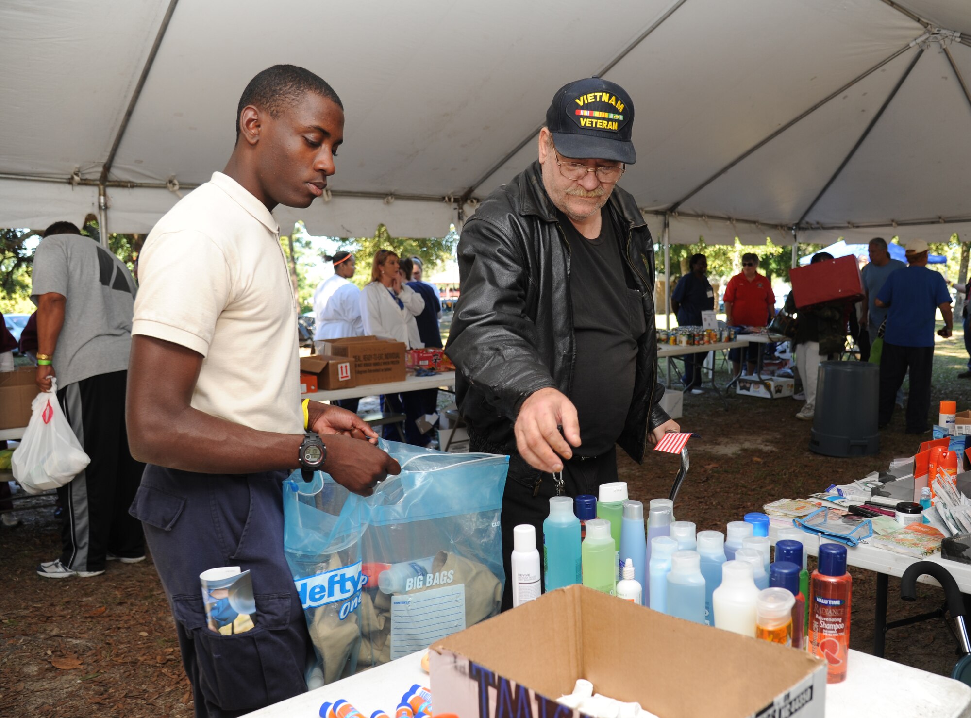 Darius Wash, Mississippi Youth Challenge Academy student at Camp Shelby, Miss., assists  Army veteran Gary MacLean with hygiene products during the 2014 Homeless Veteran Stand Down Oct. 16, 2014, at Hiller Park, Biloxi, Miss.  The Stand Down, sponsored by VA, local veteran organizations and other community organizations, provided medical services and information to homeless Veterans and families of homeless Veterans. The veterans received medical screenings, flu shots, VA social work services, a hot meal, haircuts, clothing, boots and blankets. MacLean served from 1969-1976.  (U.S. Air Force photo Kemberly Groue)
