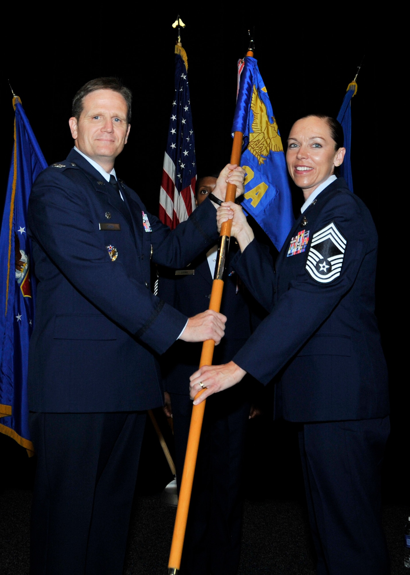 Col. Jefferson S. Dunn, Thomas N. Barnes Center for Professional Military Education commander at Maxwell Air Force Base, Ala., passes the Paul W. Airey NCO Academy guidon to Chief Master Sgt. Juliet C. Gudgel, Paul W. Airey NCOA commandant, during a change of command ceremony Oct. 16 at the NCOA auditorium. Gudgel is responsible for the overall operation of the academy, preparing instructor staff through in-service training, formulating academy policy and implementing Air Force and enlisted PME procedures. (U.S. Air Force photo by Airman 1st Class Sergio A. Gamboa)