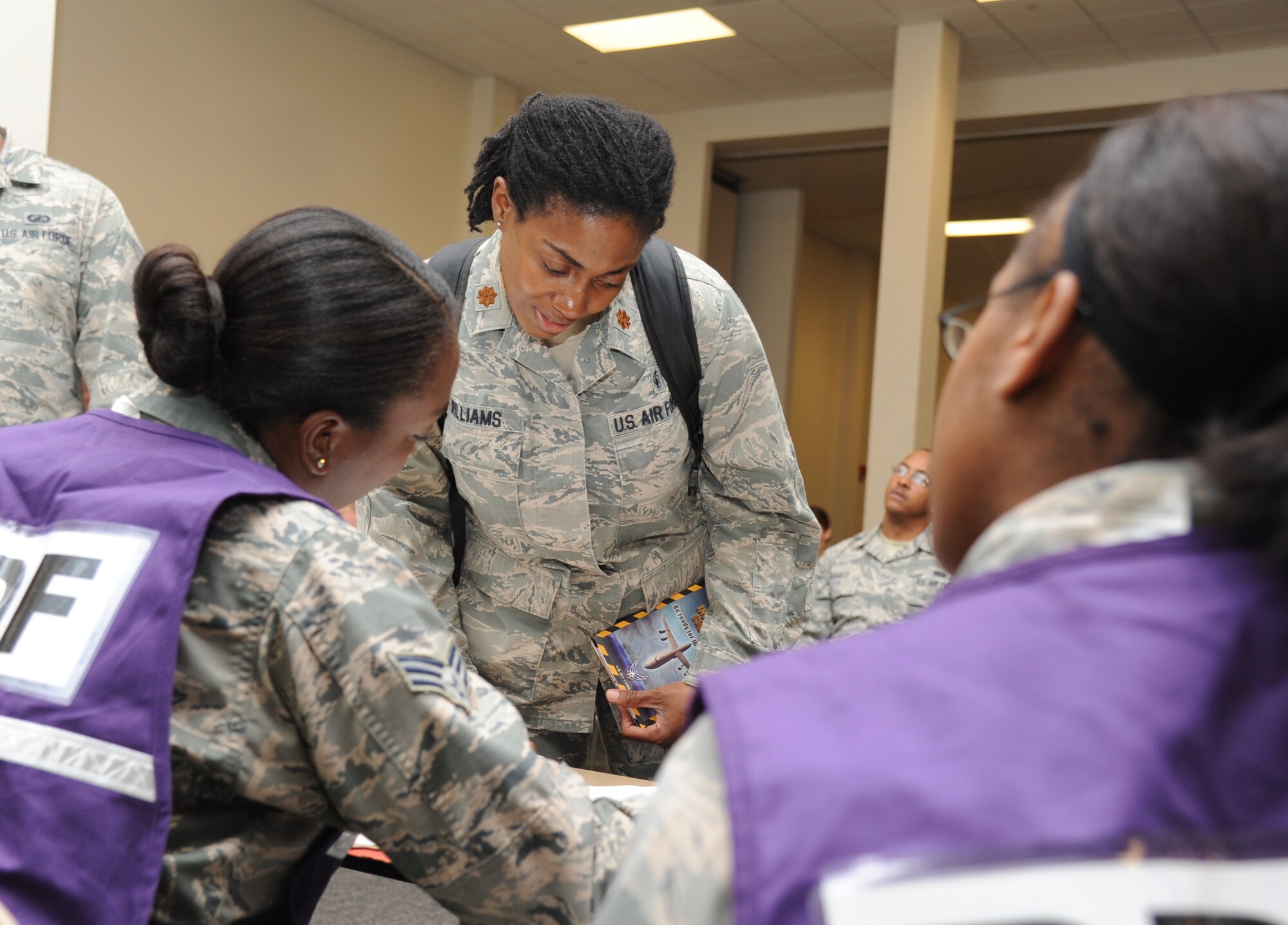 Maj. Karen Williams, 81st Medical Operations Squadron, receives assistance from Senior Airmen Ashleigh Early and Kay-Ann Wright-Donaldson, 81st Force Support Squadron, with reviewing her mobility records and personal identification information as she processes through the deployment eligibility line during a humanitarian deployment exercise Oct. 16, 2014, at the Roberts Consolidated Aircraft Maintenance Facility, Keesler Air Force Base, Miss. The exercise scenario tested the mission readiness of Team Keesler members for world-wide deployments.. (U.S. Air Force photo by Kemberly Groue)