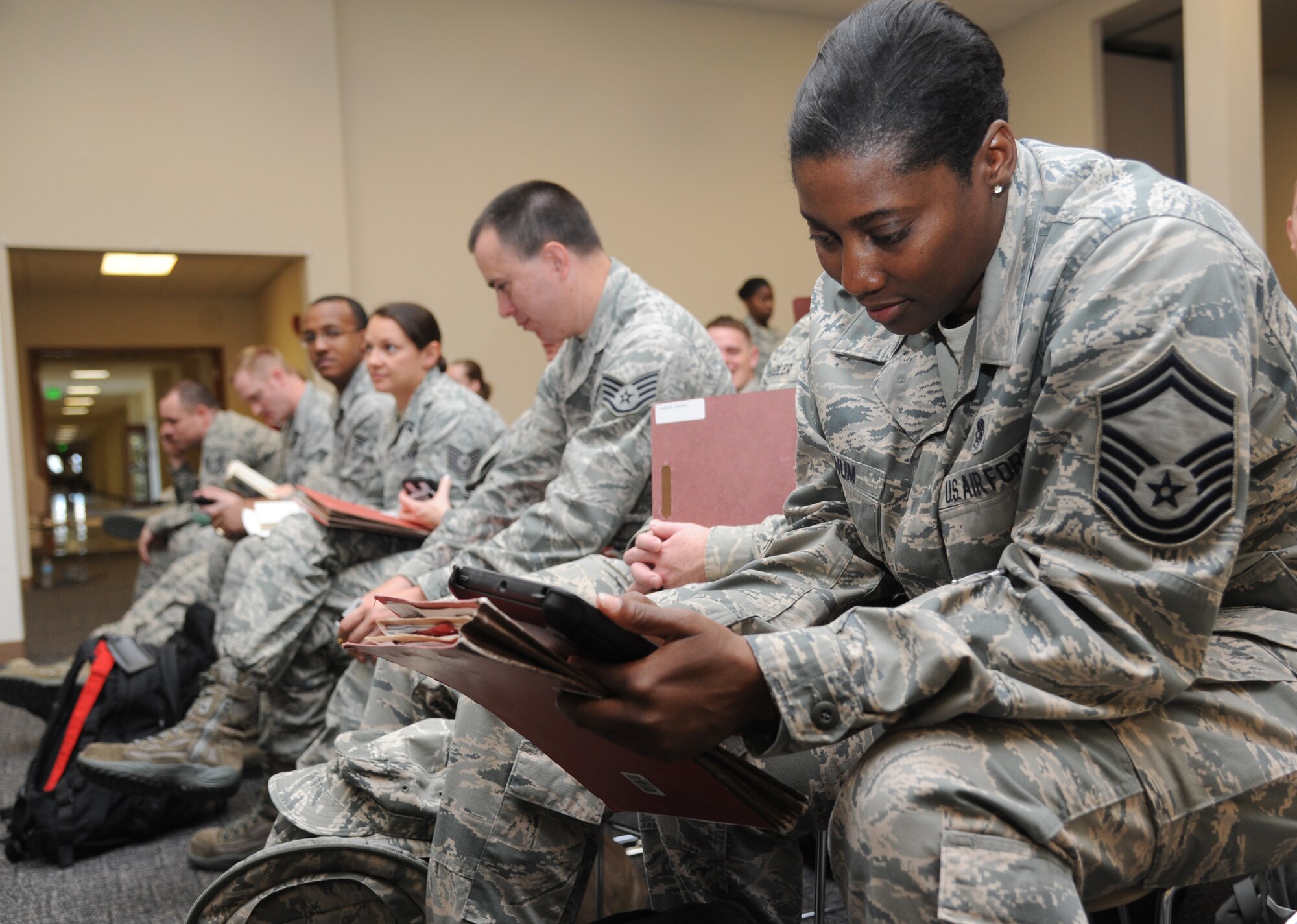 Senior Master Sgt. Lisbeth Farnum, 81st Aerospace Medicine Squadron, and fellow Airmen prepare their mobility records and personal identification information prior to processing through the deployment eligibility line during a humanitarian deployment exercise Oct. 16, 2014, at the Roberts Consolidated Aircraft Maintenance Facility, Keesler Air Force Base, Miss. The exercise scenario tested the mission readiness of Team Shaw Keesler for world-wide deployments. (U.S. Air Force photo by Kemberly Groue)