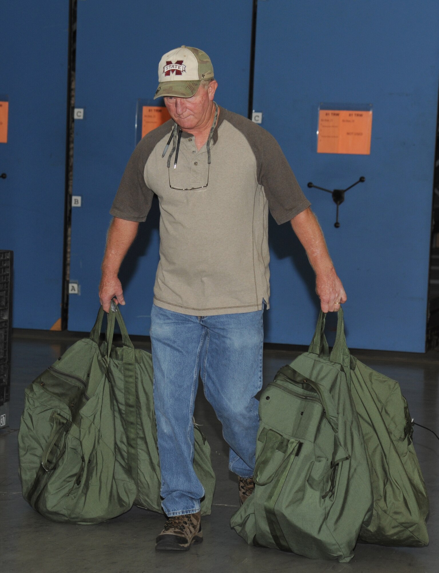 Phil Dearman, Base Operations Support contractor, carries a set of mobility bags for separating and storing issued equipment following a bag drag at the supply warehouse during a humanitarian deployment exercise Oct. 16, 2014, at the Taylor Logistics Center, Keesler Air Force Base, Miss.  The exercise scenario tested the mission readiness of Team Keesler members for world-wide deployments. (U.S. Air Force photo by Kemberly Groue)
