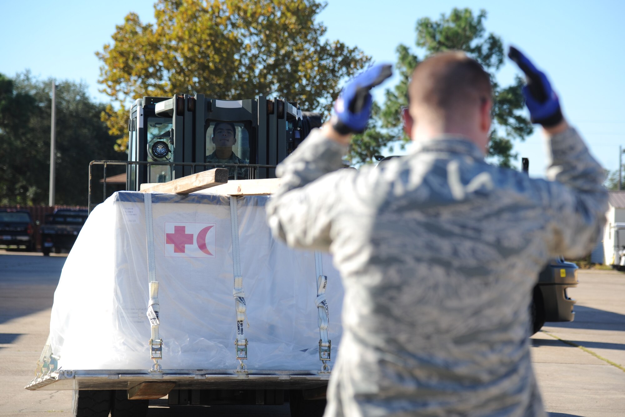Senior Airman Jason Lillis, 81st Logistics Readiness Squadron, provides direction to Airman 1st Class Daniel Litardo, 81st LRS, as he operates a forklift for transporting cargo at the supply warehouse loading docks during a humanitarian deployment exercise Oct. 15, 2014, at the Taylor Logistics Center, Keesler Air Force Base, Miss.  The exercise scenario tested the mission readiness of Team Keesler members for world-wide deployments. (U.S. Air Force photo by Kemberly Groue)