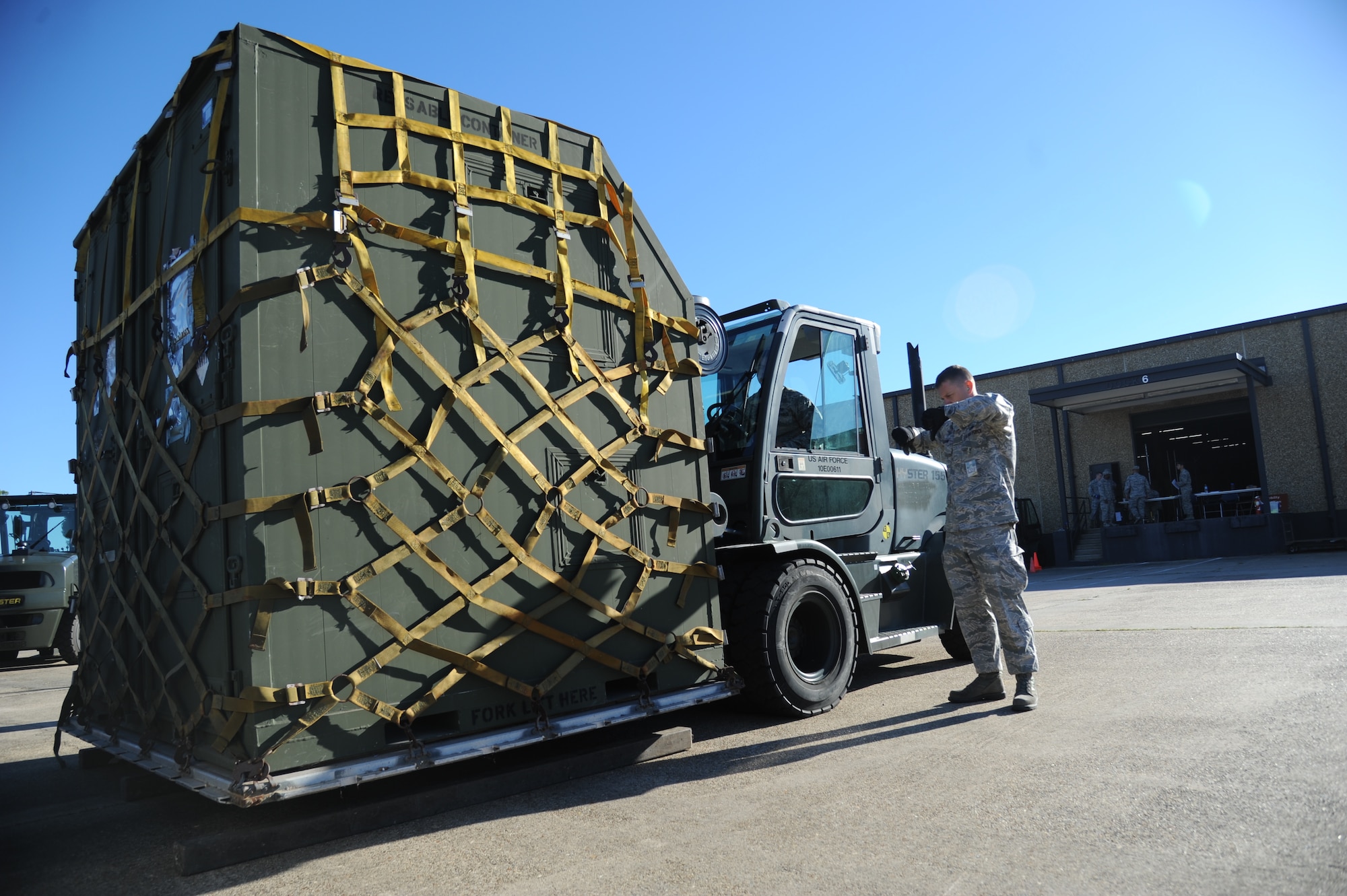 Staff Sgt. David Frahm, 81st Logistics Readiness Squadron, provides direction to Airman 1st Class Daniel Litardo, 81st LRS, as he operates a forklift for transporting cargo at the supply warehouse loading docks during a humanitarian deployment exercise Oct. 15, 2014, at the Taylor Logistics Center, Keesler Air Force Base, Miss.  The exercise tested the mission readiness of Team Keesler members for world-wide deployments. (U.S. Air Force photo by Kemberly Groue)