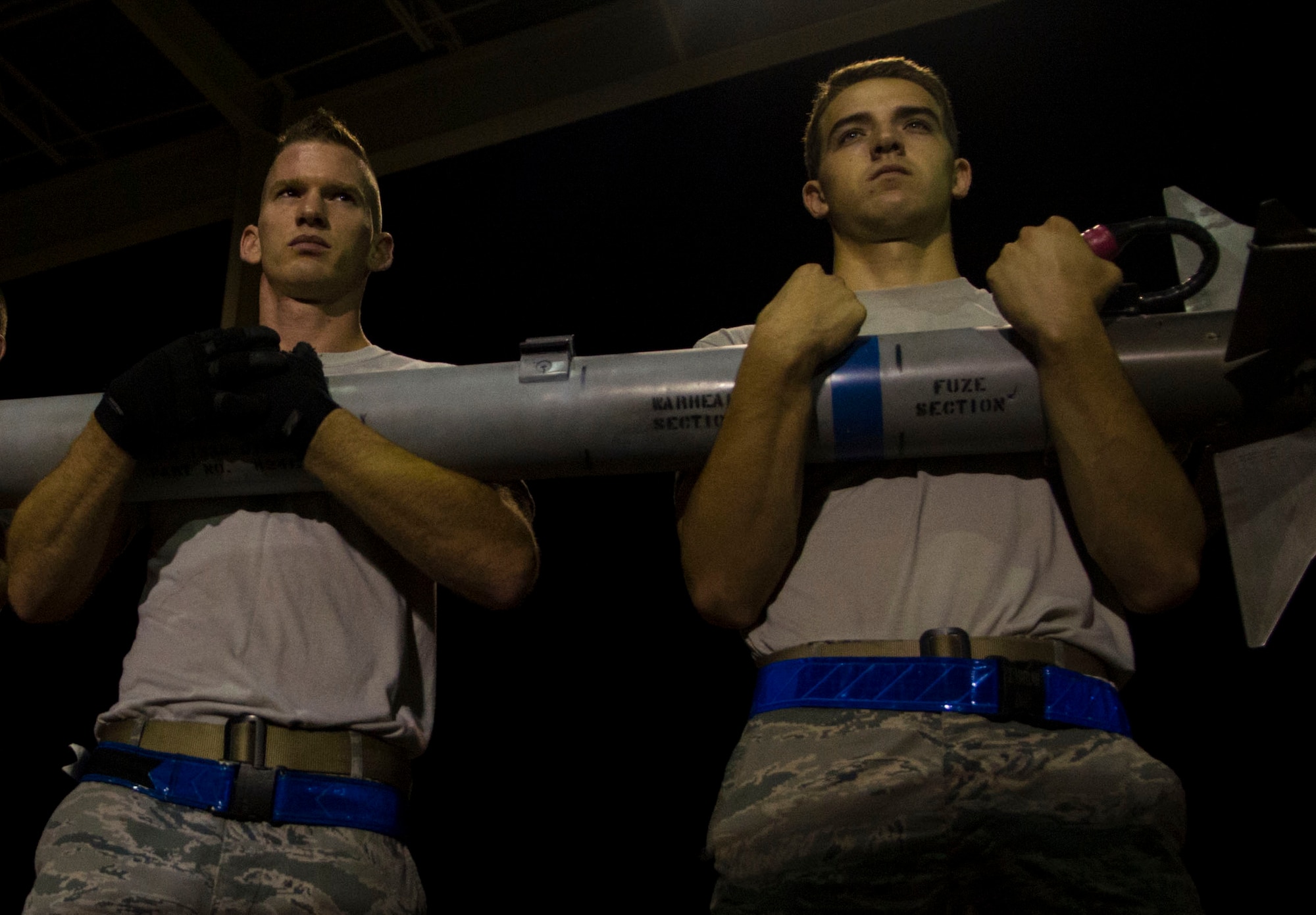 U.S. Air Force Staff Sgt. Corey Bower, 94th Air Maintenance Unit Team 25 weapons load team leader, and Airman Zach Harlan, 94th AMU weapons load crewmember, transport a munition at Langley Air Force Base, Va., Oct. 14, 2014. Each member of a three-Airman munitions team has specific duties to properly load an aircraft, and Airmen do not often move between positions within the team. (U.S. Air Force photo by Senior Airman Austin Harvill/Released)