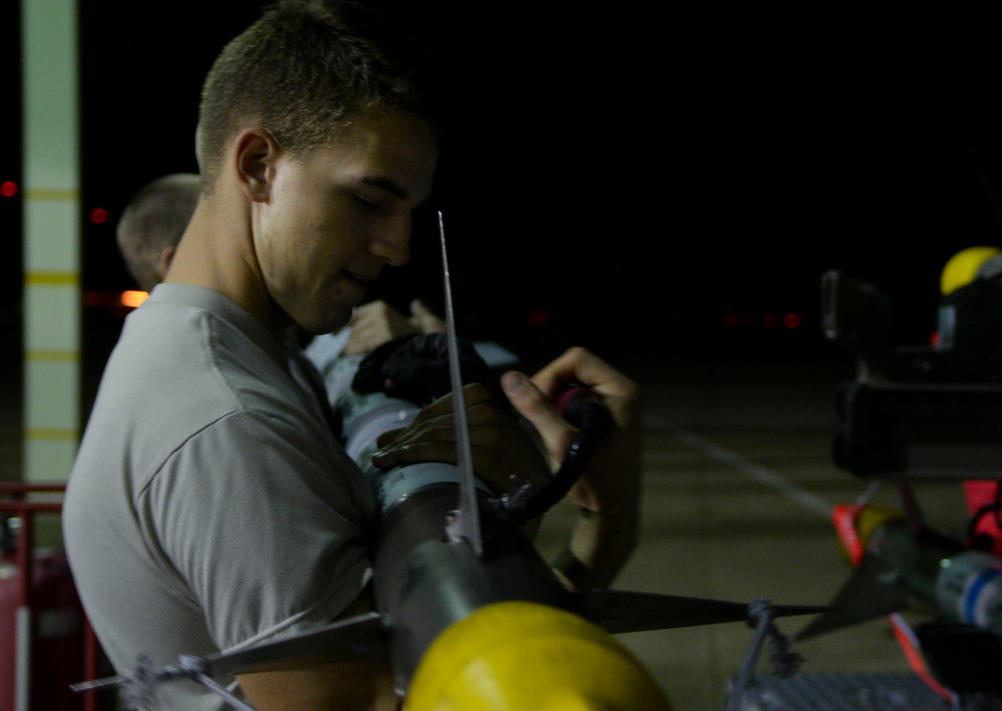 U.S. Air Force Airman Zach Harlan, 94th Air Maintenance Unit weapons load crewmember, performs the three-man carry with Team 25 at Langley Air Force Base, Va., Oct. 14, 2014. Weighing in around 150 pounds, three people are necessary to move the munition safely. (U.S. Air Force photo by Senior Airman Austin Harvill/Released)