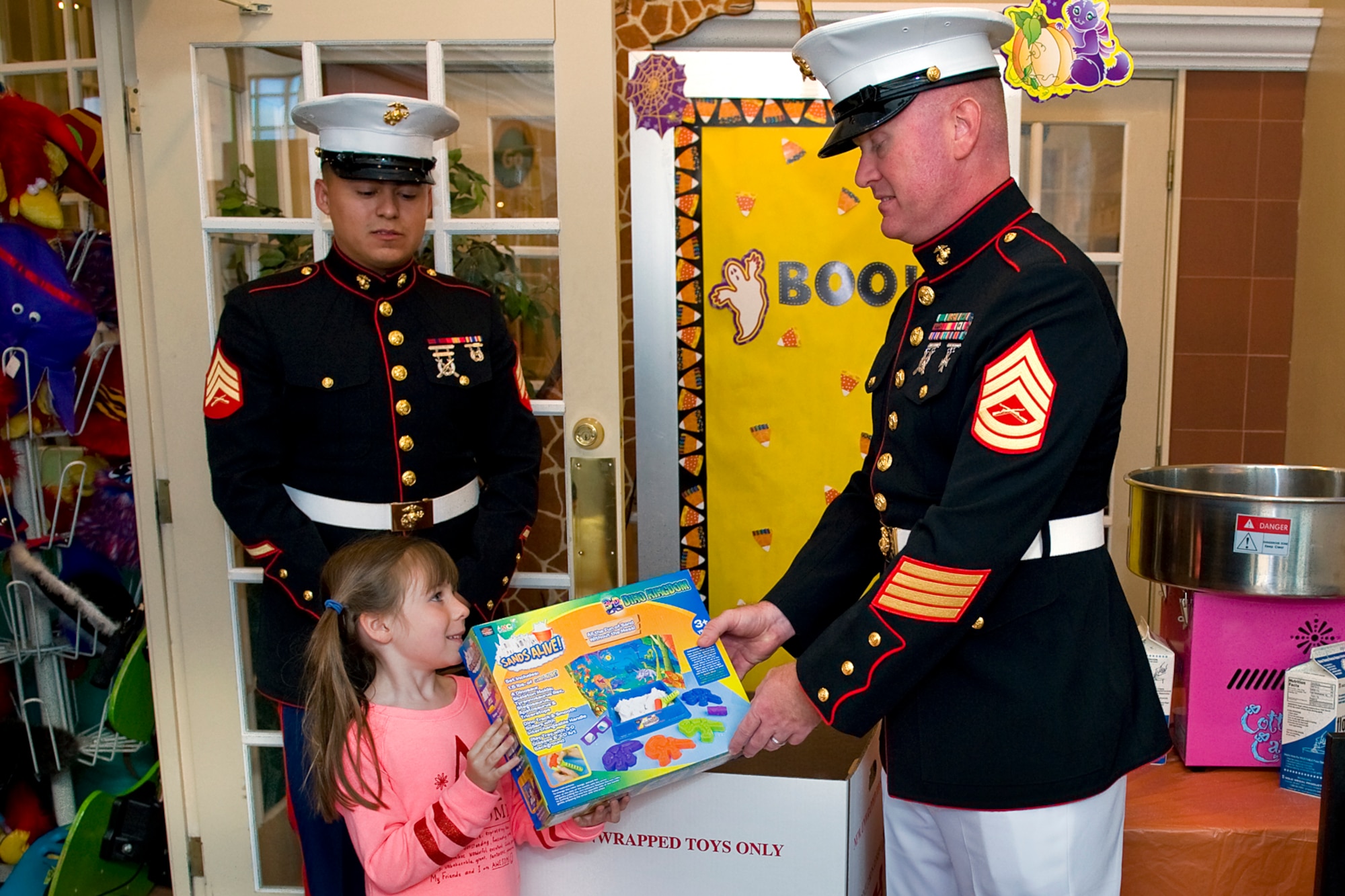 Sara McKill, 6, hands a toy to Marine Gunnery Sgt. James Schluckbier, Detachment One, Communication Company, Combat Logistics Regiment 45, 4th Marine Logistics Group electronics maintenance chief, as Marine Sgt. Javier Medina, Detachment One administrative clerk, watches during a Toys for Tots drive in Kokomo, Ind., Oct. 17, 2014. The mission of the Toys for Tots program is to collect new, unwrapped toys during October, November and December each year, and distribute those toys as Christmas gifts to less-fortunate children in the community in which the campaign is conducted. (U.S. Air Force photo/Mark R. W. Orders-Woempner)
