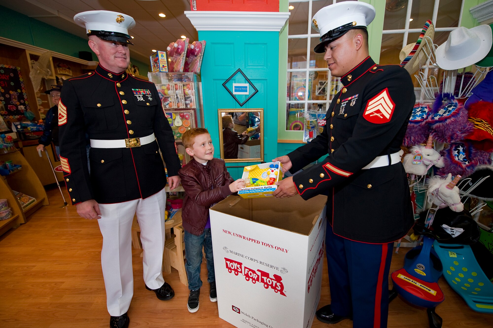 Dylon Harrell, 8, hands a toy to Marine Sgt. Javier Medina, Detachment One, Communication Company, Combat Logistics Regiment 45, 4th Marine Logistics Group administrative clerk, as Marine Gunnery Sgt. James Schluckbier, Detachment One communications electronics maintenance chief, watches during a Toys for Tots drive in Kokomo, Ind., Oct. 17, 2014. The mission of the Toys for Tots program is to collect new, unwrapped toys during October, November and December each year, and distribute those toys as Christmas gifts to less-fortunate children in the community in which the campaign is conducted. (U.S. Air Force photo/Mark R. W. Orders-Woempner)
