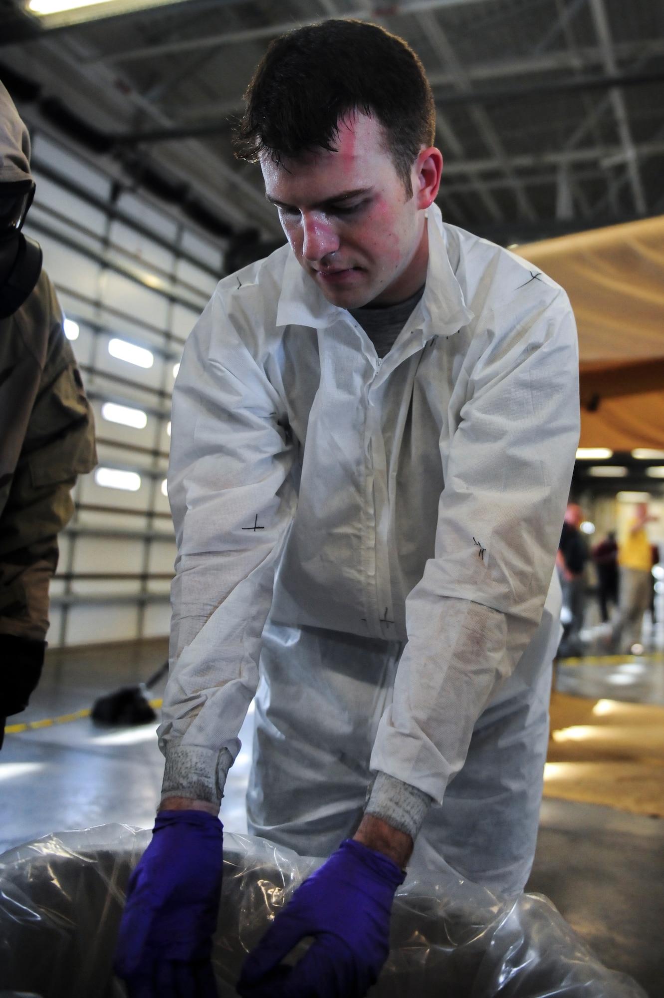 Airman 1st Class Kyle Rogers, an Aircrew Flight Equipment specialist assigned to the 355th Operations Support Squadron at Davis-Monthan Air Force Base, Arizona, removes his protective equipment as part of the decontamination process during an Air Combat Command Joint Aircrew Flight Equipment evaluation testing Oct. 14, 2014, at Seymour Johnson Air Force Base, North Carolina. Representatives from several bases including Joint Base Langley-Eustis, Ellsworth, Seymour Johnson, Beale, Tinker, Davis-Monthan, Nellis and Hill Air Force Base, were on hand to test current and future flight equipment for every aircraft in the Air Force inventory, including the newest fighter, the military's F-35 Joint Strike Fighter. (U.S. Air Force photo/Airman 1st Class Brittain Crolley)