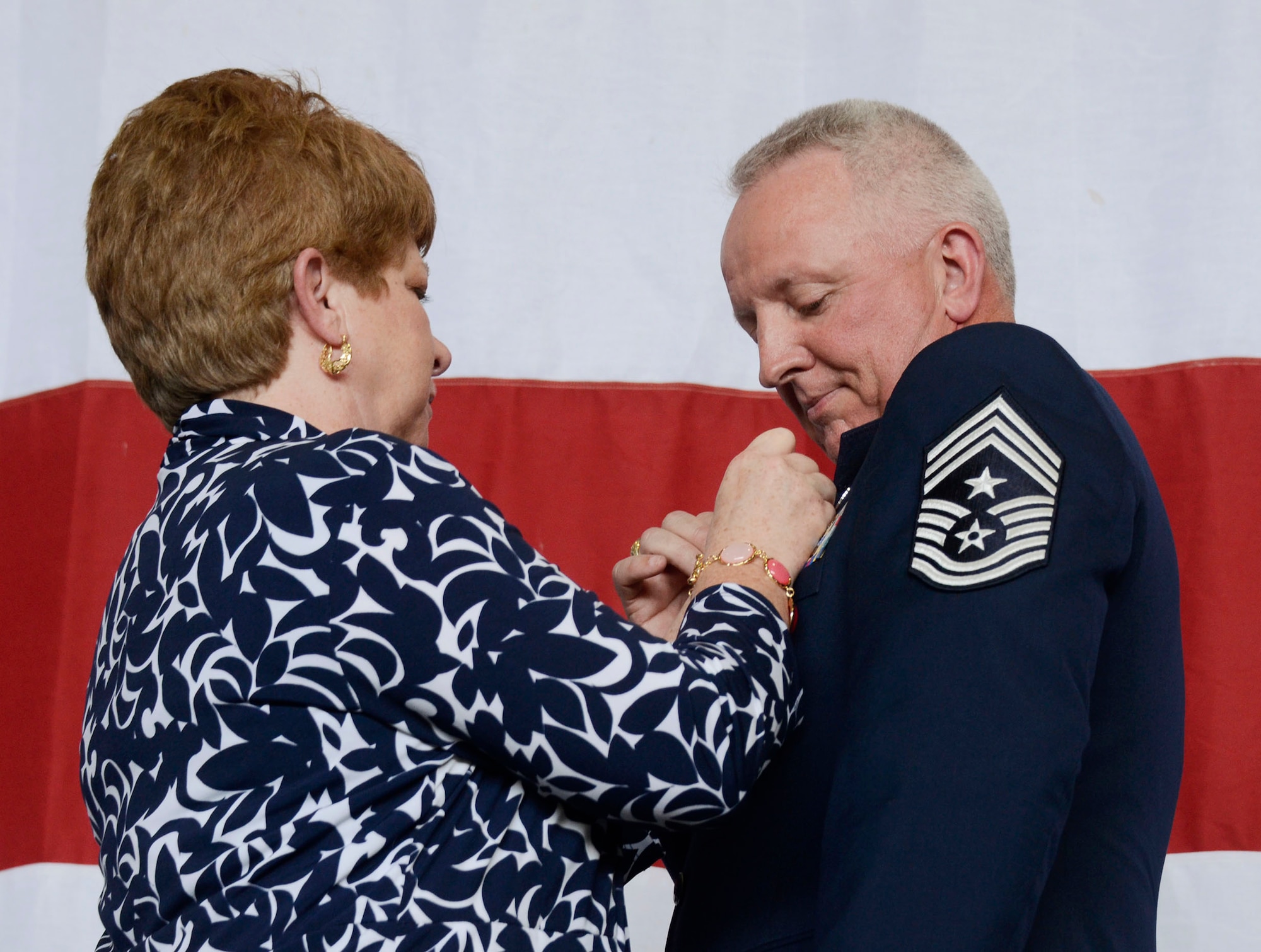 The retirement pendant is pinned on Chief Master Sgt. Wendell Peacock, 94th Airlift Wing command chief, by his wife Janet during his retirement ceremony at Dobbins Air Reserve Base, Aug. 2, 2014. Peacock retired after 33 years of service to the U.S. Air Force. (U.S. Air Force photo/Don Peek)