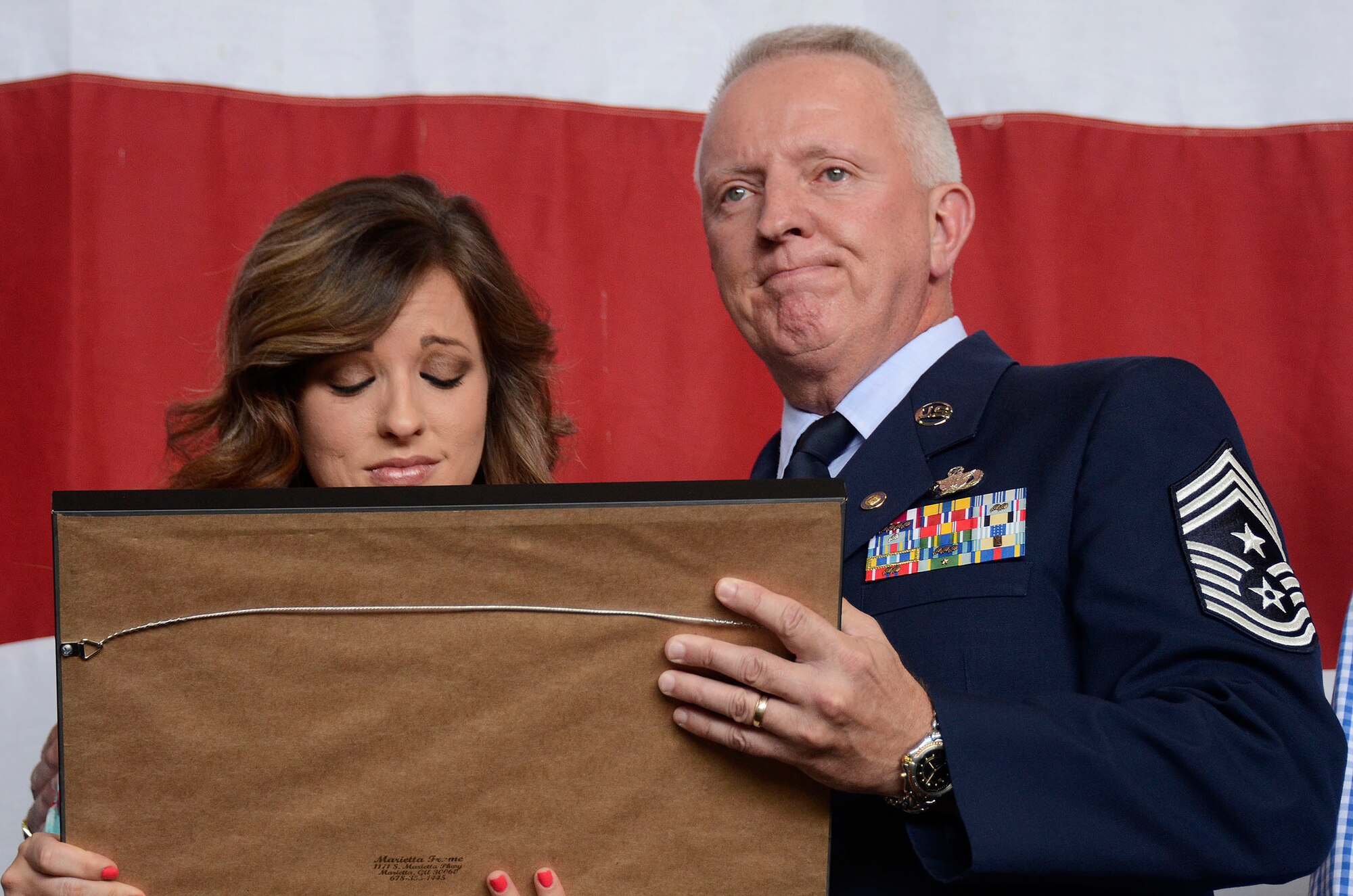 The retirement pendant is pinned on Chief Master Sgt. Wendell Peacock, 94th Airlift Wing command chief, by his wife Janet during his retirement ceremony at Dobbins Air Reserve Base, Aug. 2, 2014. Peacock retired after 33 years of service to the U.S. Air Force. (U.S. Air Force photo/Don Peek)