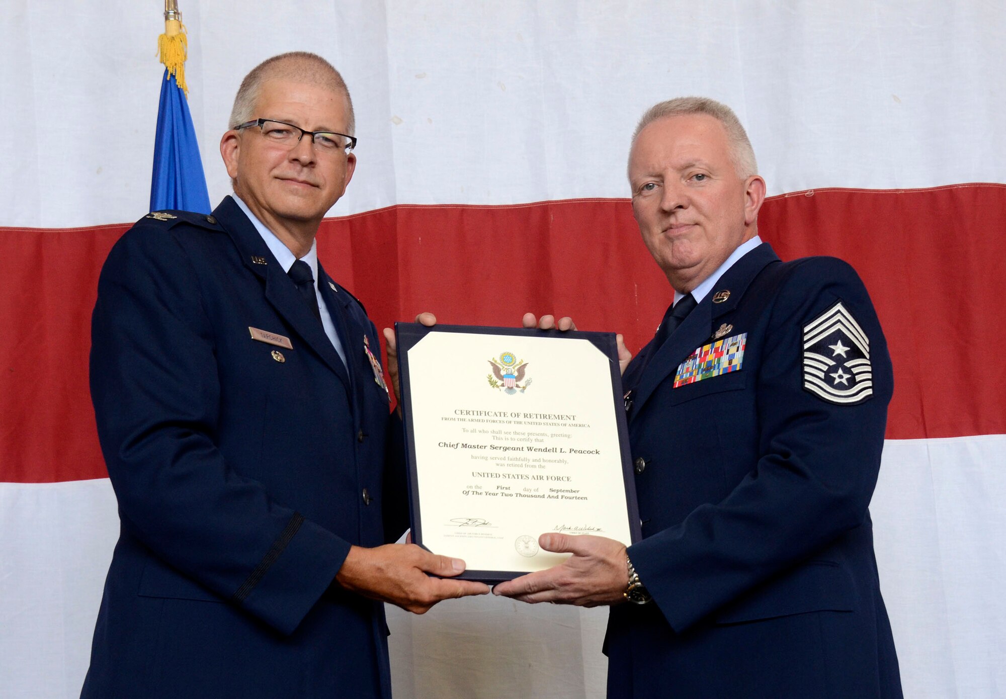 Col. (Ret) Timothy Tarchick, former 94th Airlift Wing commander, presents the certificate of retirement to Chief Master Sgt. Wendell Peacock, 94th Airlift Wing command chief, during his retirement ceremony at Dobbins Air Reserve Base, Aug. 2, 2014. “We’re here to celebrate a brave and honorable man’s career,” said Tarchick, who presided over the ceremony. “In February 2011, I hired a fantastic leader to maintain the readiness of our enlisted force - a man of character, integrity, and trustworthiness.” (U.S. Air Force photo/Don Peek)