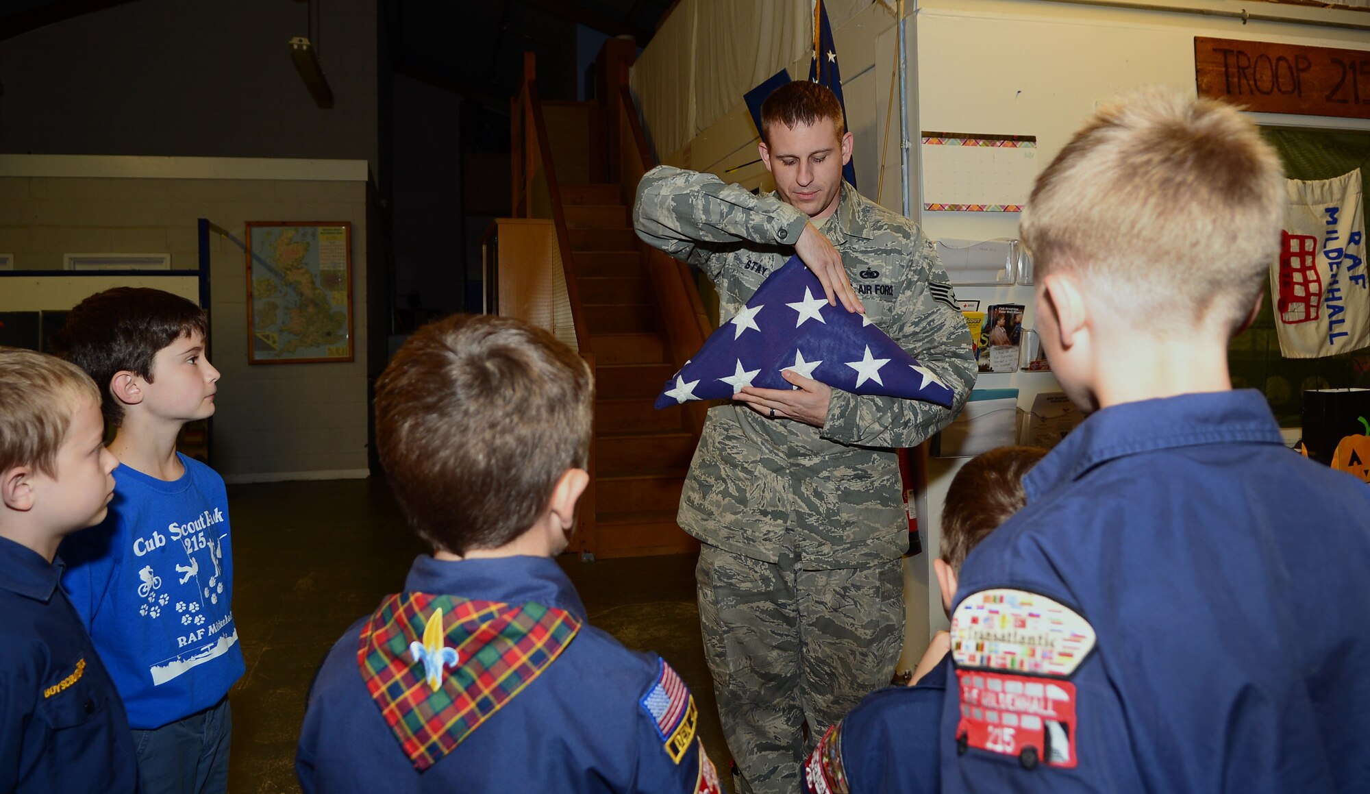 U.S. Air Force Staff Sgt. James Stay, 100th Logistics Readiness Squadron flight service center supervisor from Chicago, dresses the U.S.  flag Oct. 08, 2014, on RAF Mildenhall, England. Along with other honor guard members, Stay taught Cub Scout Pack 215 how to perform different honor guard duties such as how to post colors and retire colors. (U.S. Air Force photo/Airman 1st Class Jonathan Light/Released) 
