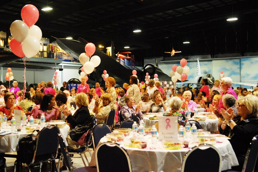 Breast cancer survivors stand for a round of applause Oct. 9 during the Houston Educare Pink Picnic at the Museum of Aviation. The event was part of Triple Ribbon Month observances promoting Breast Cancer awarenesss, represented by the Pink Ribbon; Domestic Violence, represented by the Purple Ribbon; and Drug Demand Reduction, represented by the Red Ribbon. Col. Chris Hill, Installation commander, provided opening remarks and Dr. Ava Beaudoin, Houston Healthcare radiologist, discussed the importance of breast exams. (U.S. Air Force photo by Misuzu Allen)