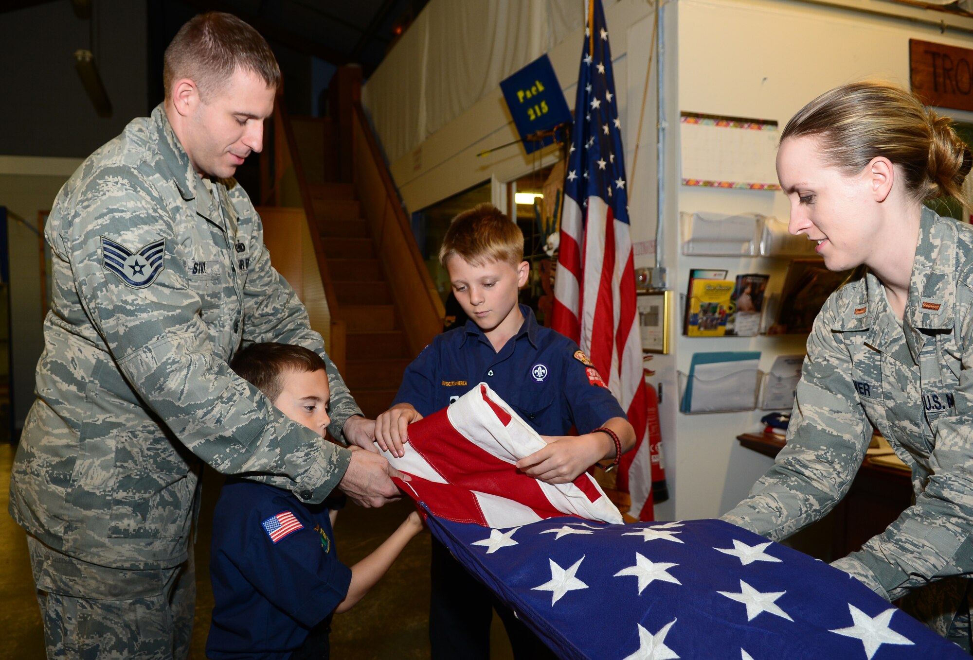 Team Mildenhall Honor Guard members teach Cub Scout Pack 215 how to fold a U.S. Flag Oct. 8, 2014, on RAF Mildenhall, England. The honor guard taught Pack 215 how to perform different honor guard duties such as how to post colors and retire colors. (U.S. Air Force photo/Airman 1st Class Jonathan Light/Released)