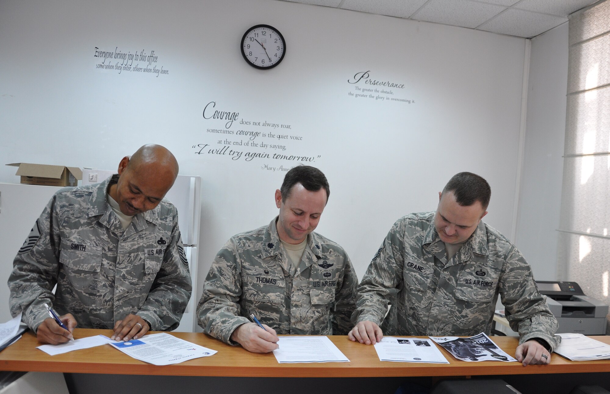 Lt. Col. John Thomas (middle), 425th Air Base Squadron commander, Master Sgt. Mark Smith (left), 425th ABS first sergeant, and Master Sgt. John Crane (right), 425th ABS superintendent, review the Combined Federal Campaign material with the intent of e-giving to save $14 in processing fees per paper donation form Oct. 17, 2014.The CFC is the only Department of Defense authorized solicitation of federal employees in the workplace on behalf of charitable organizations. (U.S. Air Force photo by Tanju Varlikli) 
