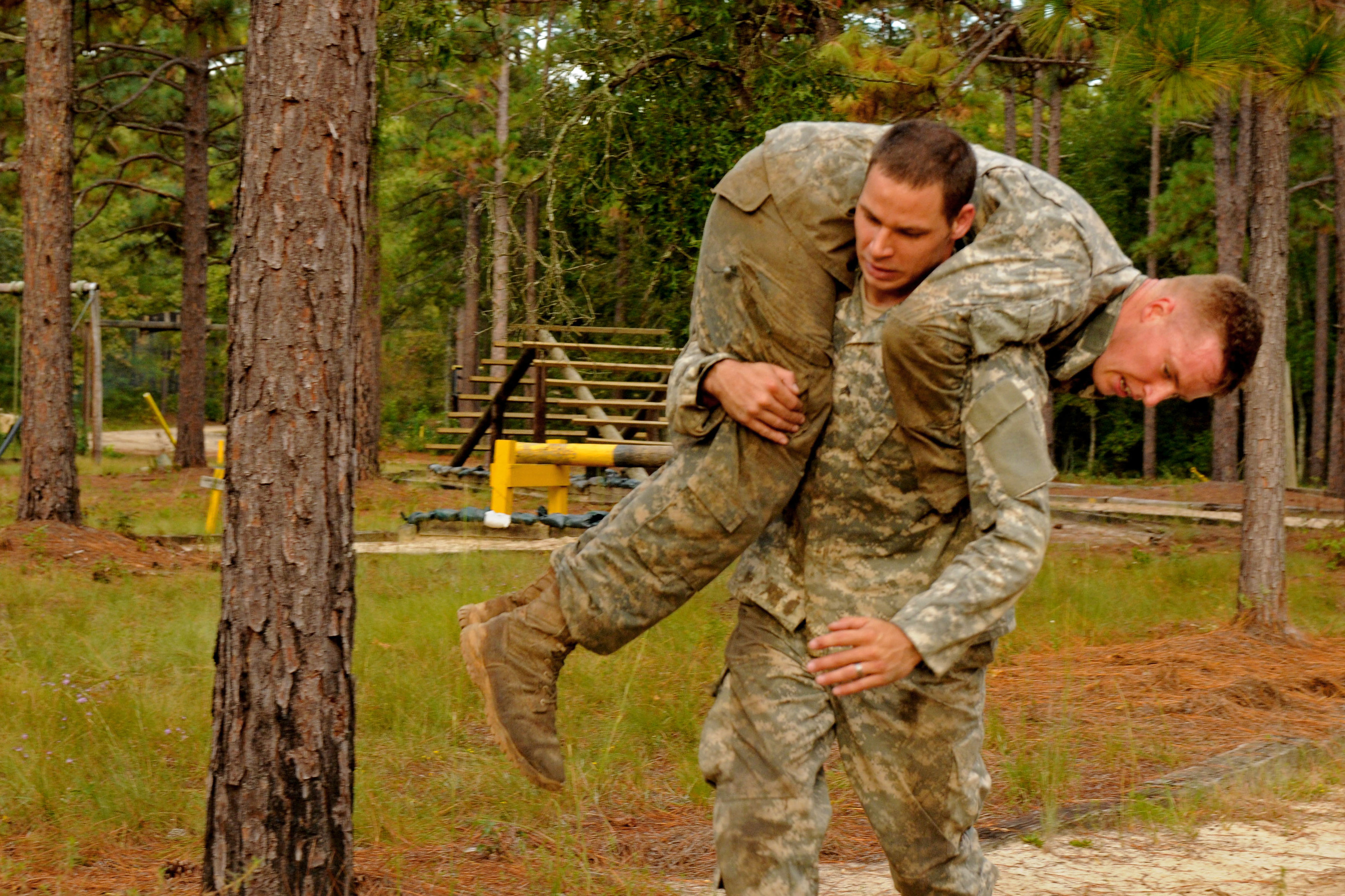 A soldier buddy carries another medic while navigating the obstacle