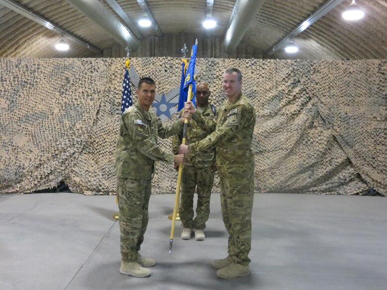 U.S.  Air Force Col. Rhude Cherry, 451st Air Expeditionary Group commander gives command of the 451st Expeditionary Operations Support Squadron to Lt. Col. James Mansard during an activation ceremony Sept. 30, 2014 at Kandahar Airfield, Afghanistan. Cherry activated the squadron when he uncased the 451 EOSS guidon. (U.S. Air Force courtesy photo/Released)