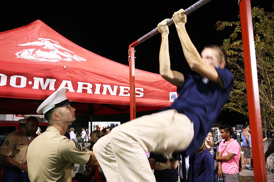 Sgt. Charles McDonald, Recruiter from Recruiting Substation Myrtle Beach, Recruiting Station Columbia, watches on as a student attempts to do pull-ups during the football game between South Florence High School and Carolina Forest High School Oct. 17, 2014, in Myrtle Beach, S.C. (Official Marine Corps photo by Cpl. John-Paul Imbody)