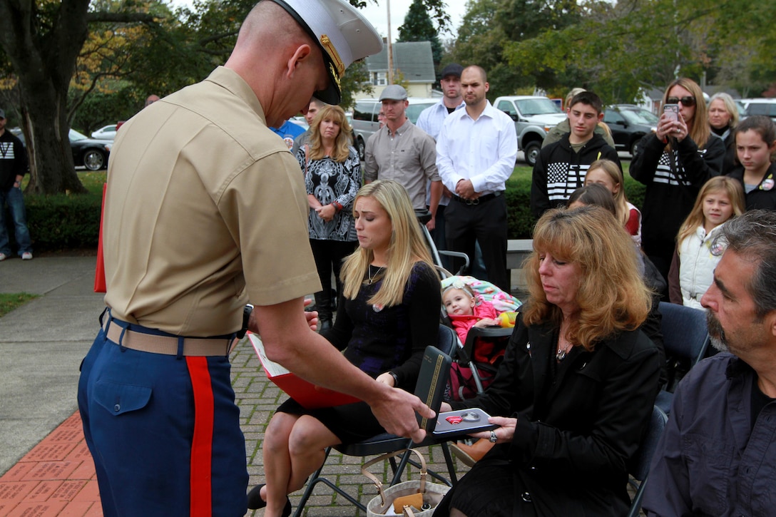 Maj. James Nolan, Inspector-Instructor for Headquarters and Service Company and Weapons Company, 1st Battalion, 25th Marine Regiment, presents the Bronze Star Medal with Combat Distinguishing Device to Karen Vasselian during a ceremony Oct. 13, in front of the American Legion’s Lewis V. Dorsey Post 112 War Memorial in Abington, Mass. Karen’s son, Sgt. Daniel Vasselian was posthumously awarded the Bronze Star Medal with Combat Distinguishing Device for combat actions while on his third deployment to Afghanistan. Daniel’s wife, Erin Vasselian, and parents, Karen and Mark Vasselian, each were presented with medals during the ceremony. Daniel was killed in action Dec. 23, 2013 in Helmand Province, Afghanistan. 