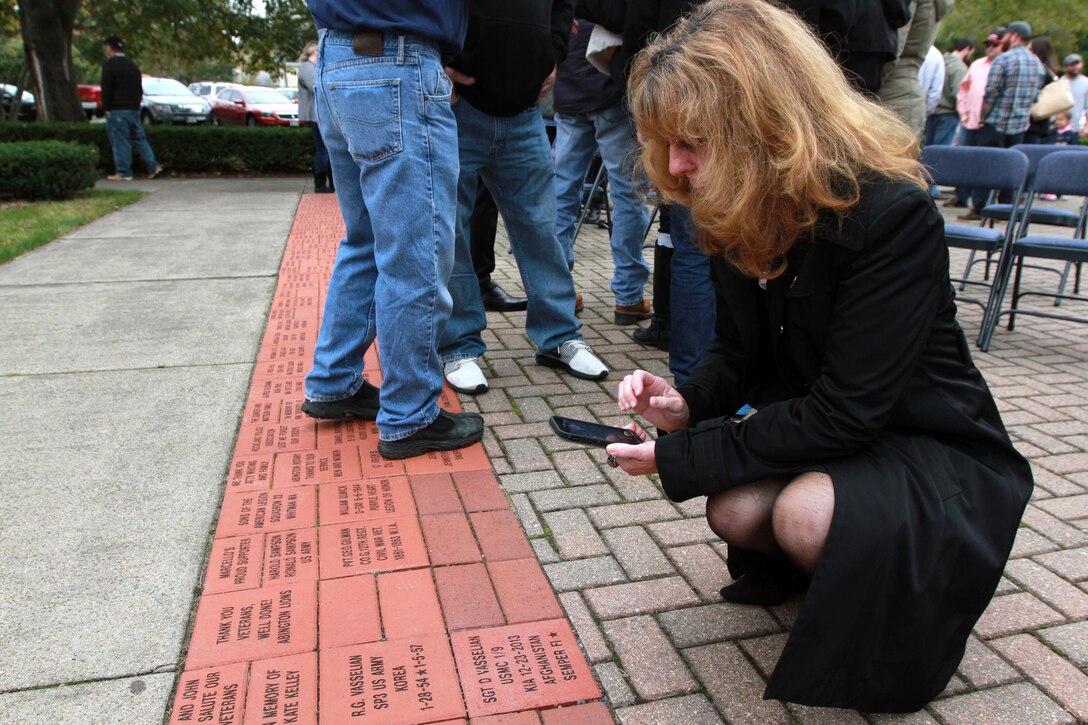 Karen Vasselian takes a photo of a commemorative brick bearing her son’s name Oct. 13, in front of the American Legion’s Lewis V. Dorsey Post 112 War Memorial in Abington, Mass. Sgt. Daniel Vasselian was posthumously awarded the Bronze Star Medal with Combat Distinguishing Device for combat actions while on his third deployment to Afghanistan. Daniel’s wife, Erin Vasselian, and parents, Karen and Mark Vasselian, each were presented with medals during the ceremony. Daniel was killed in action Dec. 23, 2013 in Helmand Province, Afghanistan. 