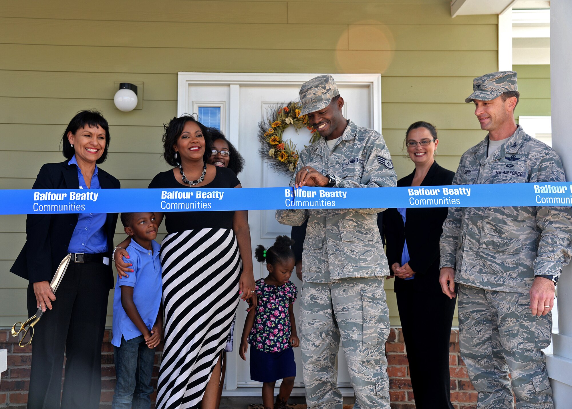 U.S. Air Force Staff Sgt. Cleon Windley, 27th Special Operations Support Squadron host aviation resource manager, and his family cut the ribbon at a ceremony Balfour Beatty Communities hosted Oct. 16 2014 at Cannon Air Force Base, N.M. After the ceremony, the Windley’s were given a thorough tour of their new home by members of BBC. (U.S. Air Force photo/Airman 1st Class Chip Slack)