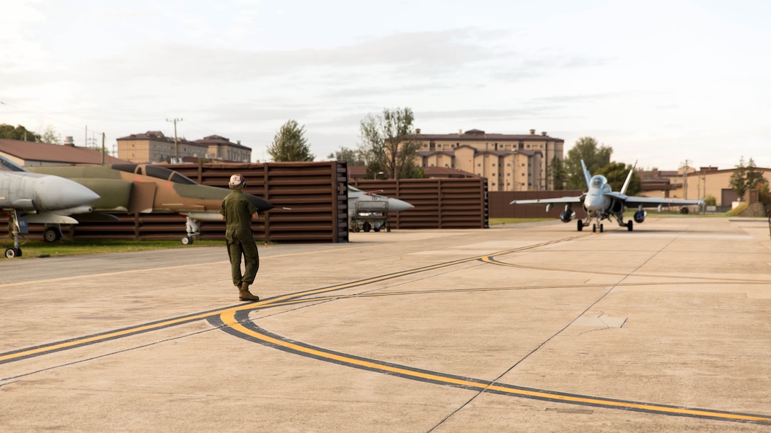 Cpl. John Deblasio, a powerline mechanic with Marine All-Weather Fighter Attack Squadron 533, guides an F/A-18 Hornet during the Korean Marine Exchange Program 14-13, Oct. 13, 2014, on Osan Air Base, Republic of Korea. KMEP 14-13 is a multinational exercise that focuses on the integration of aviation and ground assets within the construct of a traditional Combined Arms Live Fire Exercise. Supporting units include, but are not limited to, Marine Aviation Logistics Squadron 12 and Marine Wing Support Squadron 171.
