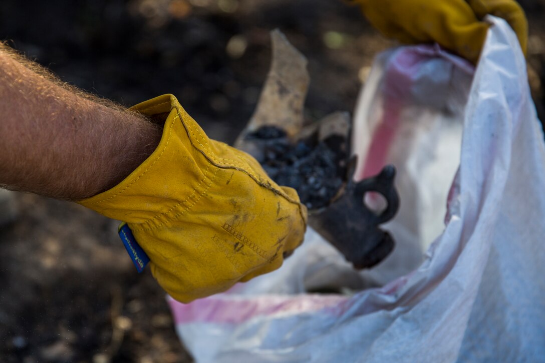 Lance Cpl. Austin Hubbar, an aviation mechanic with Marine Light Attack Helicopter Squadron (HMLA) 169, places burnt debris into a garbage bag during a Carlsbad cleanup, Oct. 18. Marines and local volunteers helped cleanup a fire-damaged area to support its ecosystem returning to normal. 