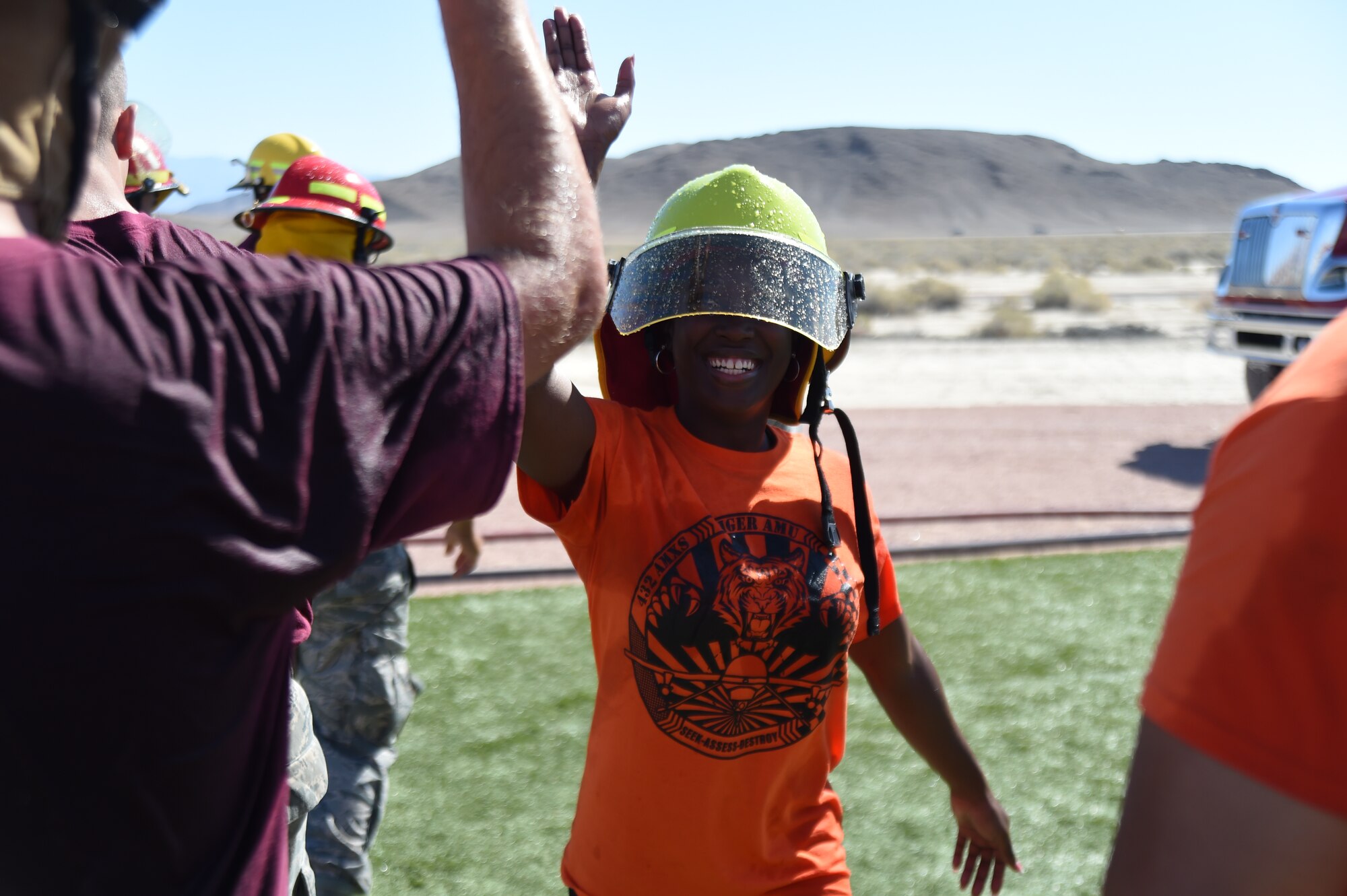 Staff Sgt. Racquel Crawford, 432nd Aircraft Maintenance Squadron team member, high fives an opposing team member after the water joust event during a fire muster challenge at Creech Air Force Base, Nevada, Oct. 10, 2014. Ten teams competed in the 4th Annual Creech AFB Fire Muster Challenge, which concluded a week-long campaign to spread fire safety awareness. (U.S. Air Force Photo by Tech. Sgt. Shad Eidson/Released)