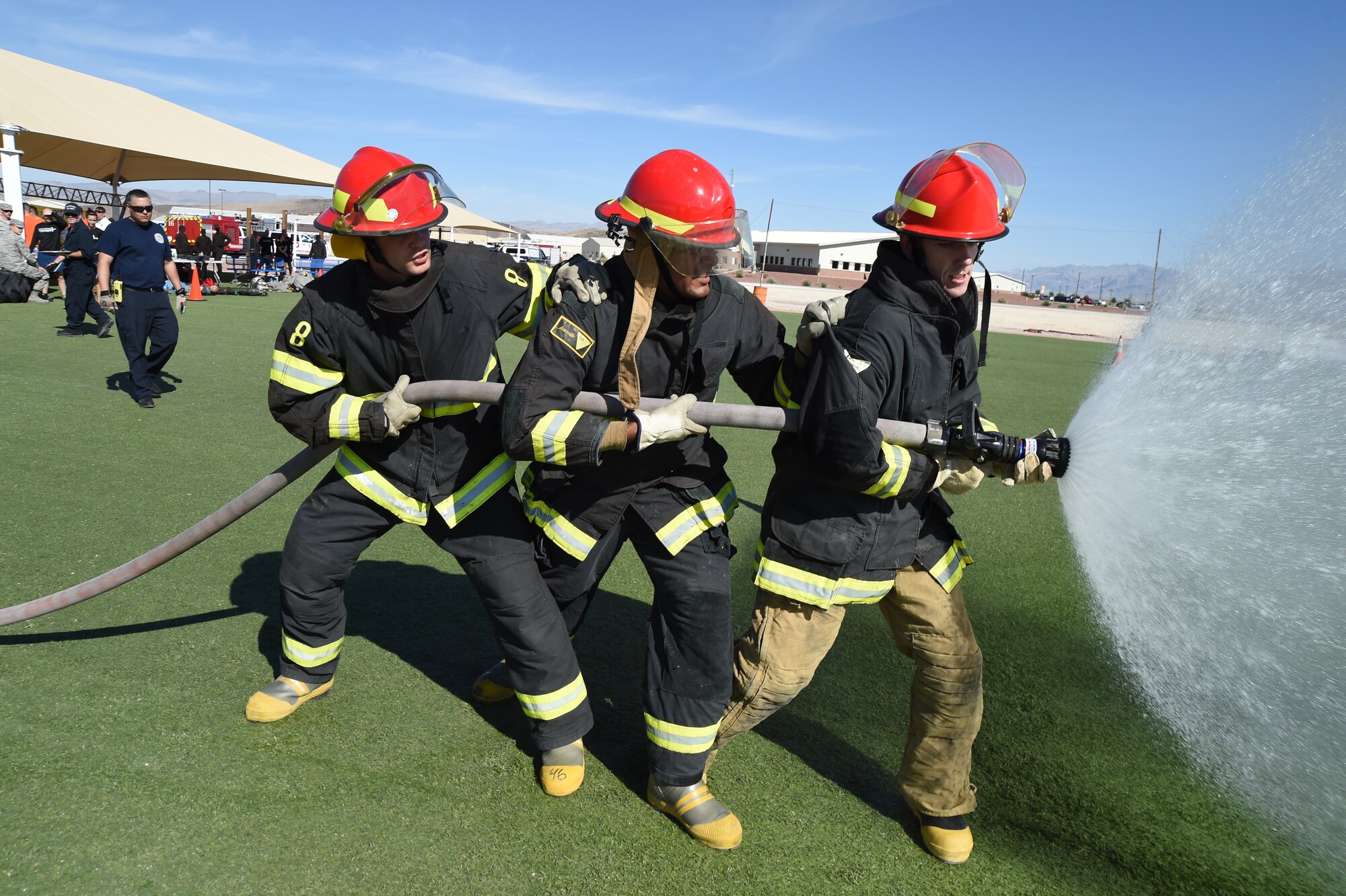 17th Reconnaissance Squadron team members aim a fire hose and try to knock down a target during a fire muster challenge at Creech Air Force Base, Nevada, Oct. 10, 2014. The 4th Annual Creech AFB Fire Muster Challenge concluded Fire Prevention Week, which promoted ‘Working Smoke Alarms Save Lives’ as this year’s theme. (U.S. Air Force Photo by Tech. Sgt. Shad Eidson/Released)