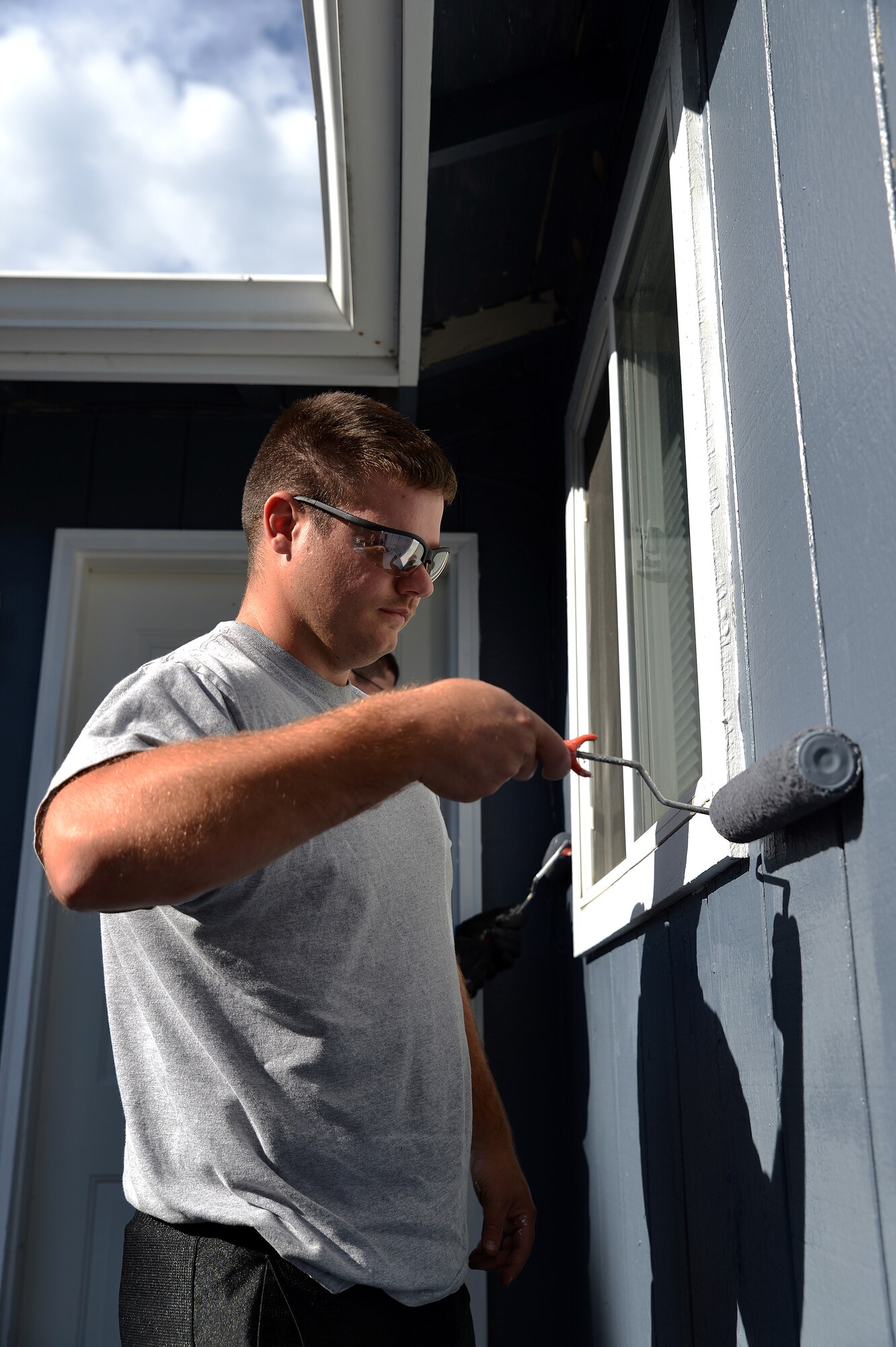 Senior Airman Johnathan Hall, 627th Civil Engineer Squadron heating, ventilation, air conditioning and refrigeration journeyman, paints the outside of a housing unit during the Thurston County Day of Service event Oct. 16, 2014, in Spanaway, Wash. The event was coordinated and hosted by the 627th Air Base Group as part of their community partnership with Thurston County to strengthen the relationship between Joint Base Lewis-McChord and the local community. (U.S. Air Force photo/Senior Airman Jacob Jimenez) 