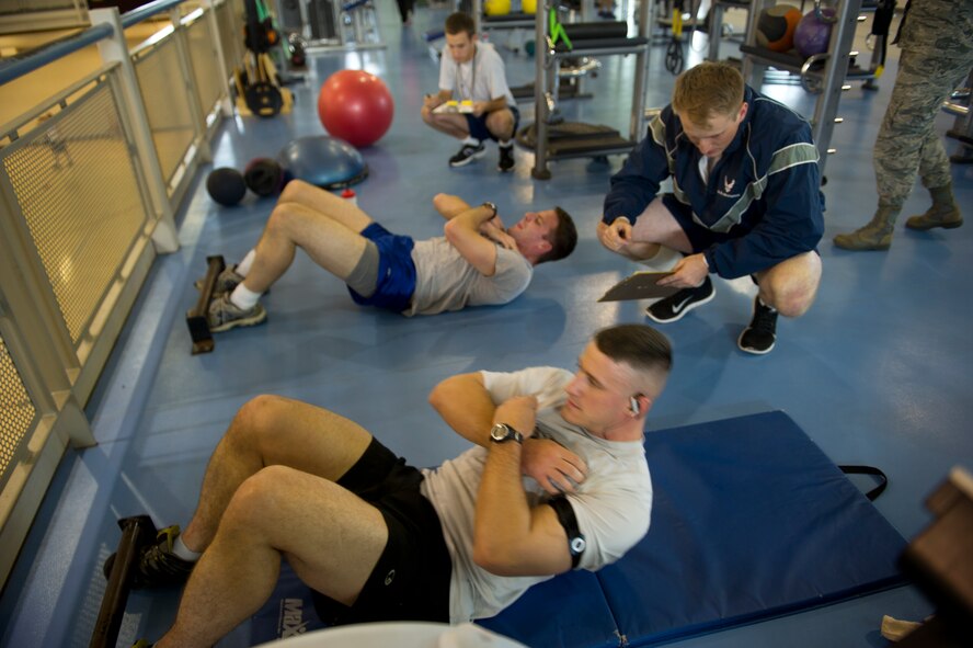 Airmen participate in the sit up portion of the Iron Airman Challenge on Minot Air Force Base, N.D., Oct. 10, 2014. The IAC is a test that consists of four events: push ups, sit ups, pull ups and a two-mile run. (U.S. Air Force photo/Senior Airman Brittany Y. Bateman)