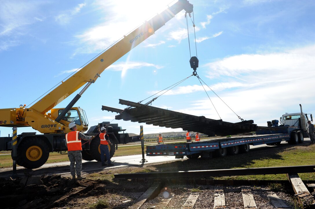 Senior Airman Scott Abkarian, 28th Civil Engineer Squadron pavements and heavy equipment journeyman, lifts railroad ties onto the bed of a truck on Highway 14/16 in Box Elder, S.D., Oct. 14, 2014. Removal of the damaged railroad tracks was a joint effort between Ellsworth and Box Elder, and demonstrates just one of the many ways the base partners with the surrounding communities. (U.S. Air Force photo by Senior Airman Hailey R. Staker/Released)