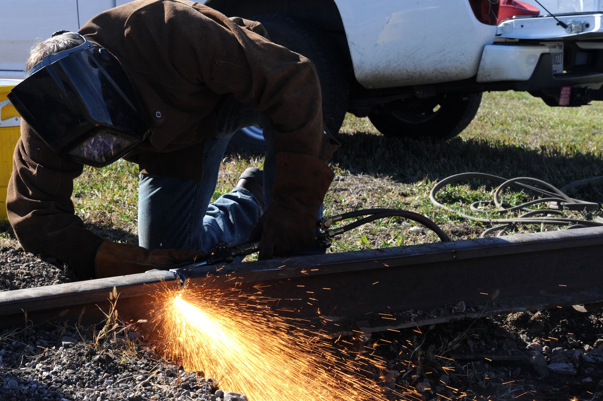 Mark Boser, 28th Civil Engineer Squadron pavements and heavy equipment welder, cuts a railroad tie on Highway 14/16 in Box Elder, S.D., Oct. 14, 2014. Civil engineer personnel partnered with Box Elder to remove the unused damaged tracks, which had become a traffic safety concern – working with local construction teams Oct 15-17. (U.S. Air Force photo by Senior Airman Hailey R. Staker/Released)