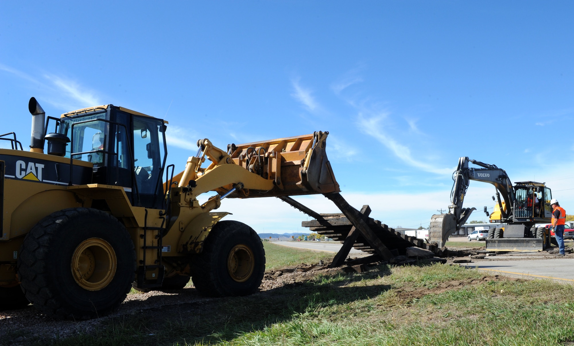 Senior Airman Edwin Clark, 28th Civil Engineer Squadron pavements and heavy equipment journeyman, lifts a section of railroad track while Kevin Holloman, 28th CES pavement and heavy equipment operator, uses an excavator to clear rubber matting on Highway 14/16 in Box Elder, S.D., Oct. 14, 2014. The 28th CES personnel partnered with the city of Box Elder to remove railroad tracks, ties and rubber matting, weighing a total of 65,000 pounds, while local construction teams repaired the road. (U.S. Air Force photo by Senior Airman Hailey R. Staker/Released)