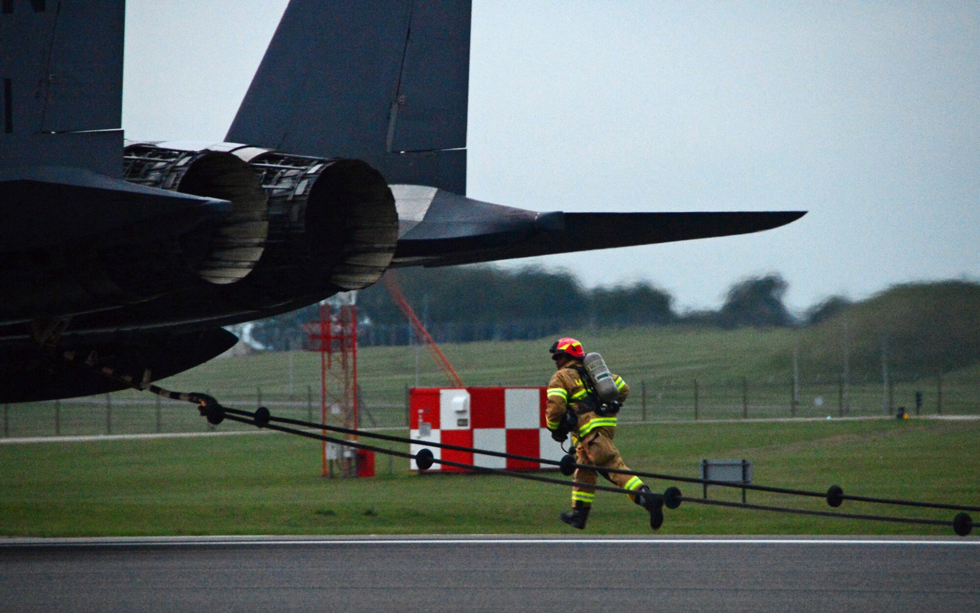 A firefighter assigned to the 48th Civil Engineer Squadron observes the exterior of a 494th Fighter Squadron F-15E Strike Eagle after the aircraft encountered a barrier engagement system as part of a certification process on the runway at Royal Air Force Lakenheath, England, Oct. 15, 2014. The cables are strategically placed along the runway to stop aircraft if hydraulic systems or brakes fail. (U.S. Air Force photo by Airman 1st Class Erin O’Shea/Released) 