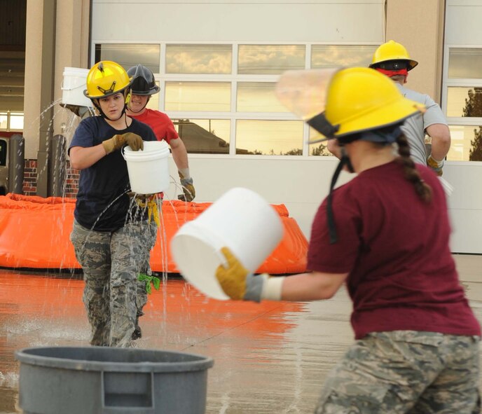 U.S. Air Force Master Sgt. Jennifer Weiss, 7th Communications Squadron first sergeant, carries a bucket of water while Senior Master Sgt. Christy Hayes, 7th Aircraft Maintenance Squadron first sergeant, dumps a bucket of water into a trash can during the Firefighter Challenge Oct. 10, 2014, at Dyess Air Force Base, Texas.  The Firefighter Challenge was one of several events held for National Fire Prevention week. The event was designed to build cohesion between the fire department and other units. (U.S. Air Force photo by Airman 1st Class Autumn Velez/Released)
