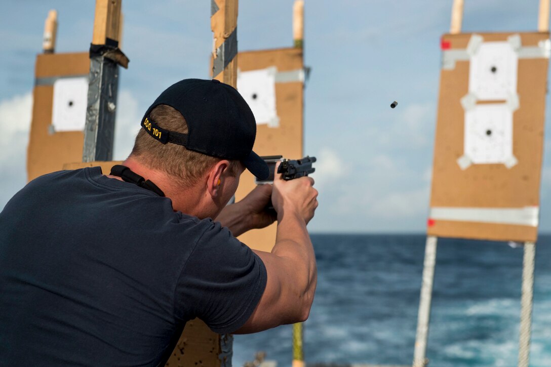 U.S. Navy Petty Officer 2nd Class Mikhail Anisimov fires an M9 service pistol during a visit, board, search and seizure exercise aboard the USS Gridley in the Indian Ocean, Oct. 11, 2014.
