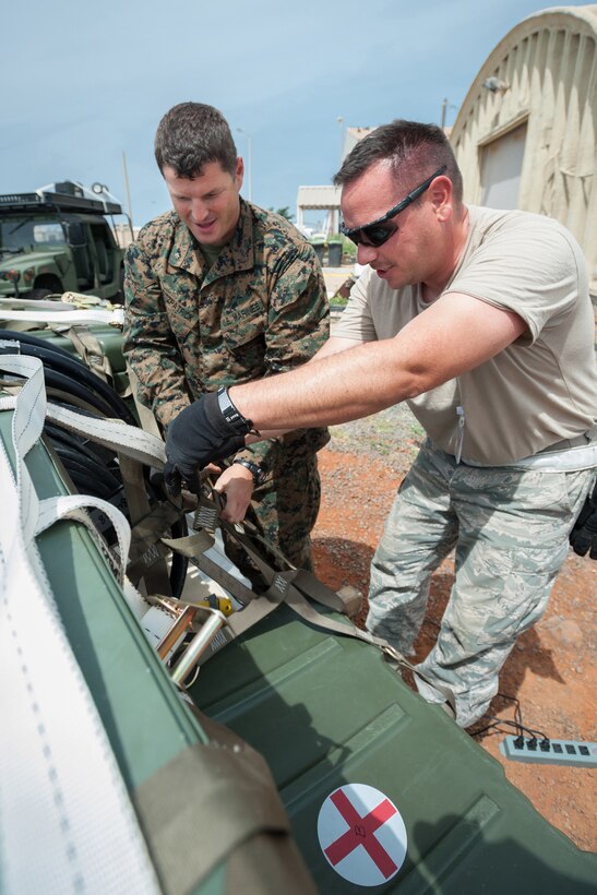 U.S. Navy Lt. Cmdr. Joseph Fitzpatrick, left, a surgeon assigned to a Forward Resuscitive Surgical System unit, and U.S. Air Force Staff Sgt. Tony Hayden, an aerial porter from the Kentucky Air National Guard’s 123rd Contingency Response Group, secure cases of red blood cells and frozen plasma to a C-130 cargo pallet at Leopold Sedar Senghor International Airport in Dakar, Senegal, Oct. 10, 2014. 