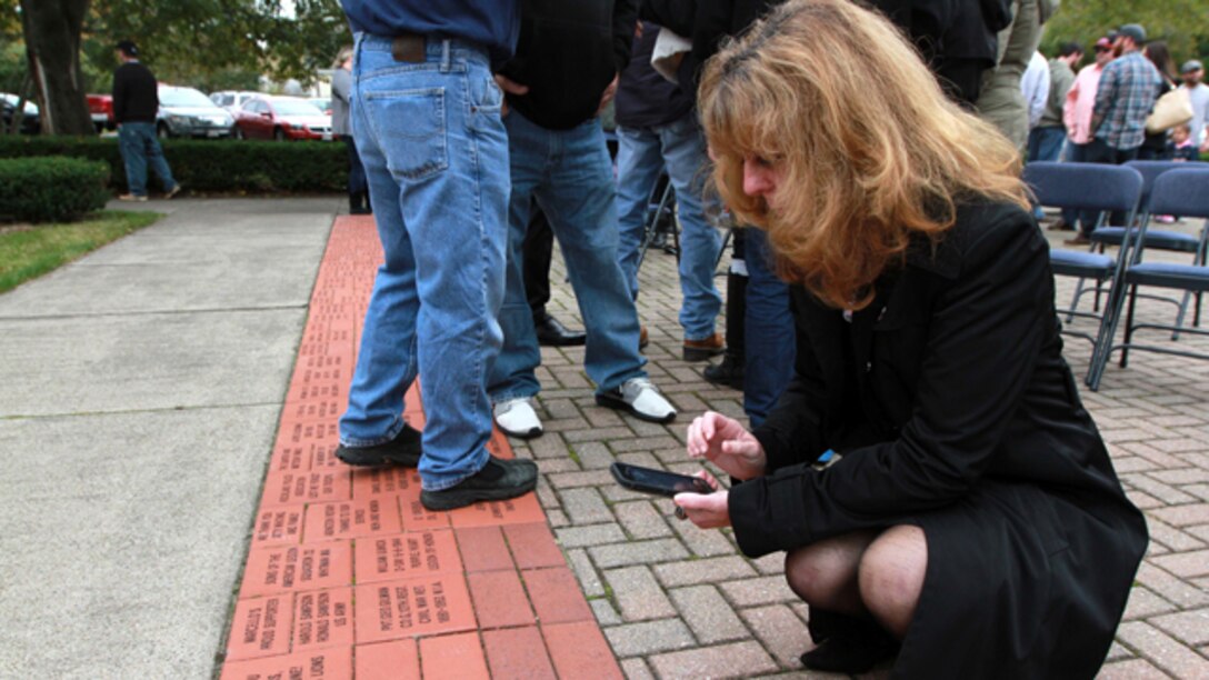 Karen Vasselian takes a photo of a commemorative brick bearing her son’s name Oct. 13, in front of the American Legion’s Lewis V. Dorsey Post 112 War Memorial in Abington, Mass. Sgt. Daniel Vasselian was posthumously awarded the Bronze Star Medal with Combat Distinguishing Device for combat actions while on his third deployment to Afghanistan. Daniel’s wife, Erin Vasselian, and parents, Karen and Mark Vasselian, each were presented with medals during the ceremony. Daniel was killed in action Dec. 23, 2013 in Helmand Province, Afghanistan. (Photo by Sgt. Richard Blumenstein)