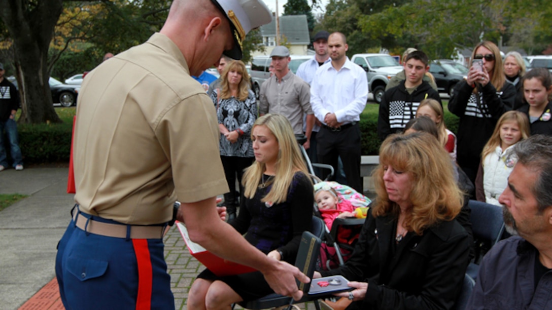 Maj. James Nolan, Inspector-Instructor for Headquarters and Service Company and Weapons Company, 1st Battalion, 25th Marine Regiment, presents the Bronze Star Medal with Combat Distinguishing Device to Karen Vasselian during a ceremony Oct. 13, in front of the American Legion’s Lewis V. Dorsey Post 112 War Memorial in Abington, Mass. Karen’s son, Sgt. Daniel Vasselian was posthumously awarded the Bronze Star Medal with Combat Distinguishing Device for combat actions while on his third deployment to Afghanistan. Daniel’s wife, Erin Vasselian, and parents, Karen and Mark Vasselian, each were presented with medals during the ceremony. Daniel was killed in action Dec. 23, 2013 in Helmand Province, Afghanistan. (Photo by Sgt. Richard Blumenstein)