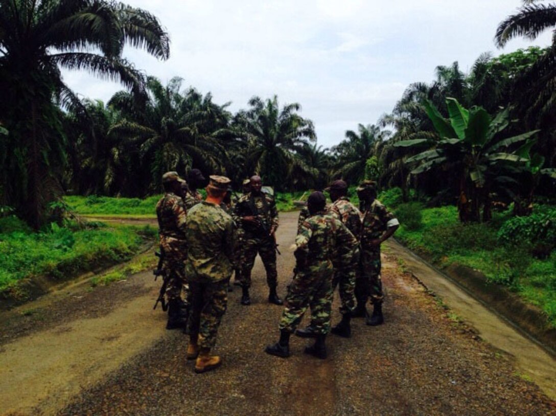 Sergeant Eduard Yakobchuk, a squad leader for Security Cooperation Team 5B, Special Purpose Marine Air Ground Task Force-Crisis Response-Africa discusses after action points with members of the Cameroonian Naval Commando Company (COPALCO), after a patrol in Cameroon, Sept. 28, 2014. SCT-5B worked with the COPALCO on marksmanship, boat operations, and patrolling. (Courtesy Photo)