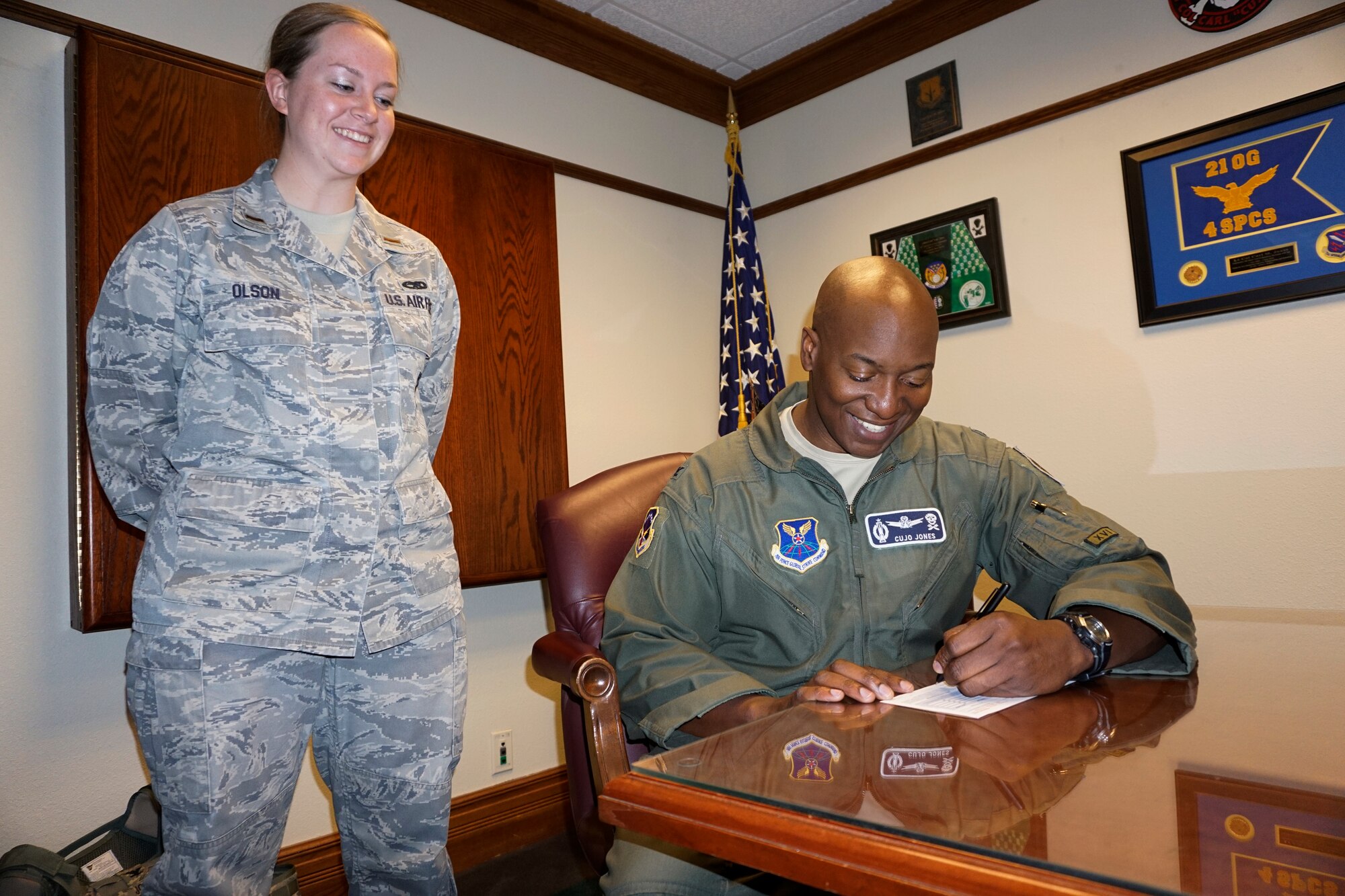 Col. Carl Jones, 90th Missile Wing vice commander, signs a Combined Federal Campaign donation pledge Oct. 14, 2014, as 2nd Lt. Megan Olson, the CFC representative watches on F.E. Warren Air Force Base, Wyo. The CFC is a charity campaign funded by the donations of federal employees. (U.S. Air Force photo by Lan Kim)