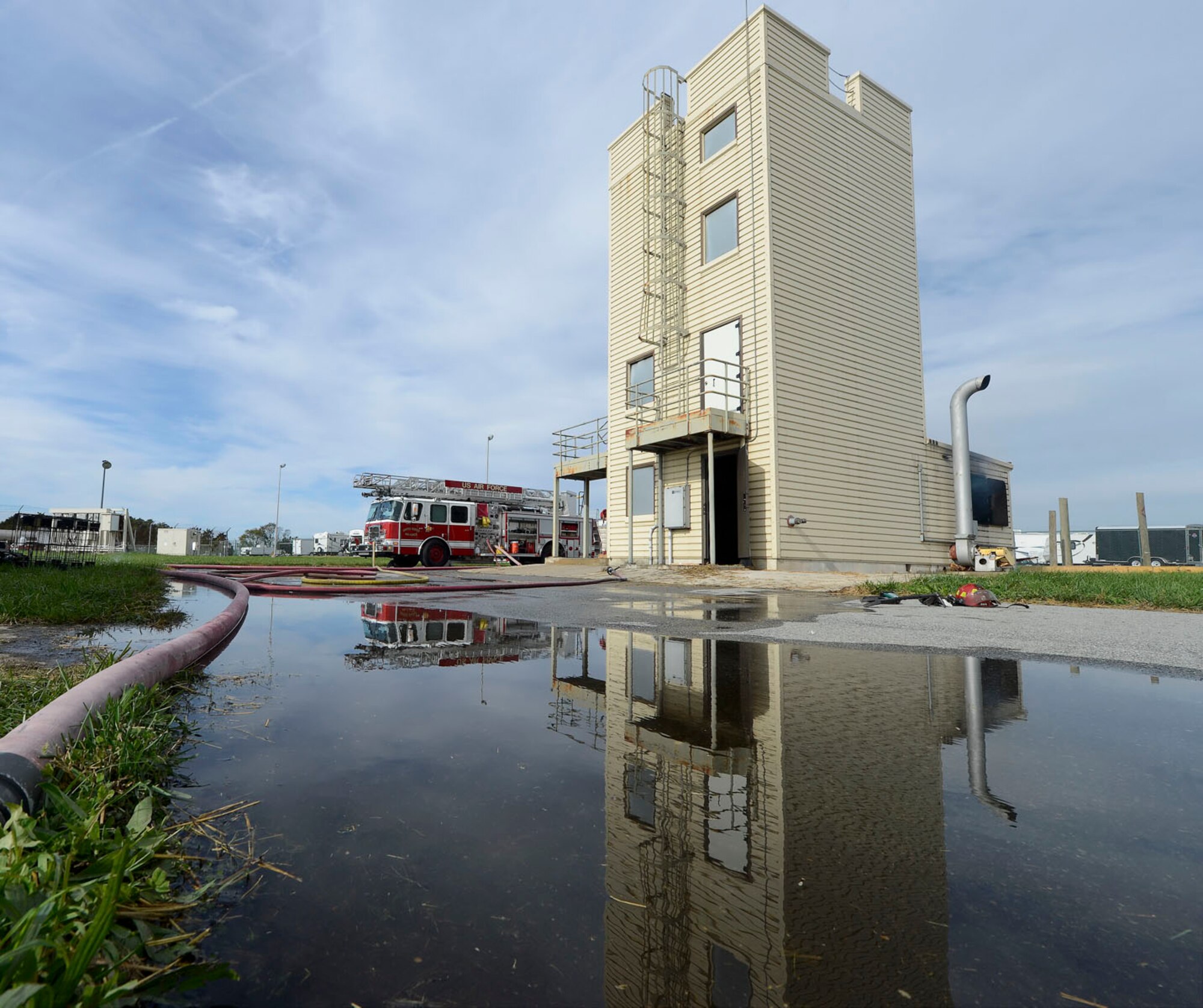 Reflections of the fire training facility, a fire engine along with hoses can be seen in a pool of water following a training exercise by the 436th Civil Engineer Squadron Fire Department Oct. 20, 2014, at Dover Air Force Base, Del. This multi-story, specially-built fire training structure allows conditions to be controlled to maximize training and safety. (U.S. Air Force photo/Greg L. Davis)