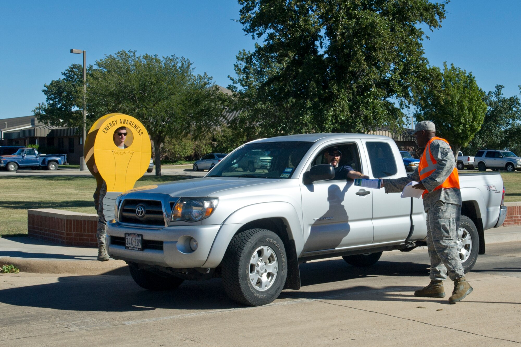 GOODFELLOW AIR FORCE BASE, Texas -- Tech. Sgt. Desmond S. Williams, 17th Civil Engineer Squadron programs flight NCO in charge, hands out energy awareness flyers at the North gate Oct. 14. October is Energy Action Month. (U.S. Air Force photo/ Staff Sgt. Laura R. McFarlane)