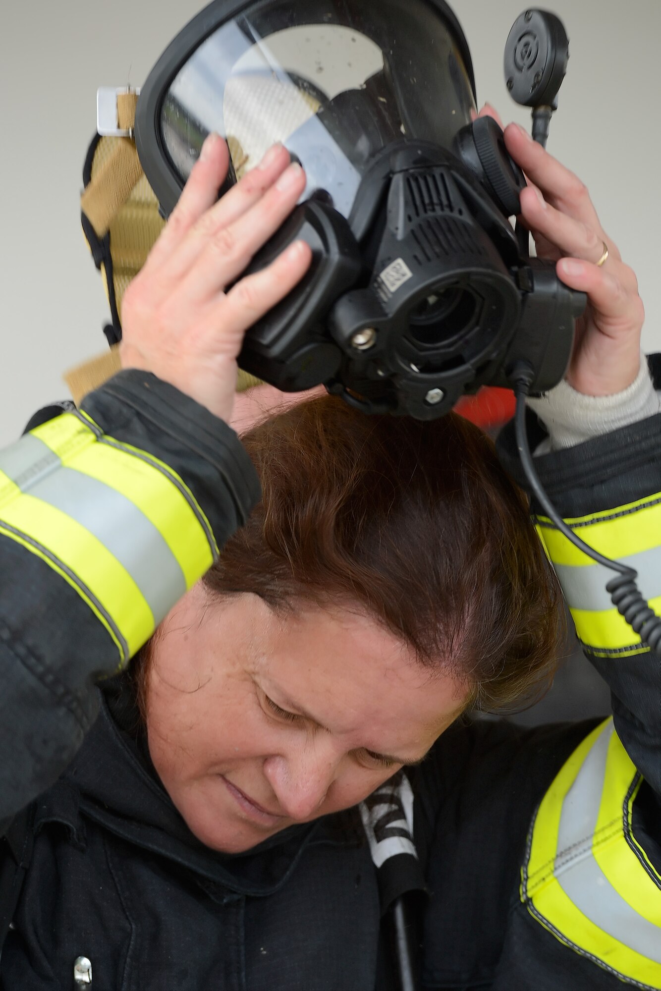 Gina Lavender, 436th Civil Engineer Squadron deputy commander, doffs her fire-protection mask after completing a training evolution at the structural fire training facility Oct. 20, 2014, at Dover Air Force Base, Del. Lavender took part in the training to experience first-hand the challenging conditions faced by firefighters. (U.S. Air Force photo/Greg L. Davis)