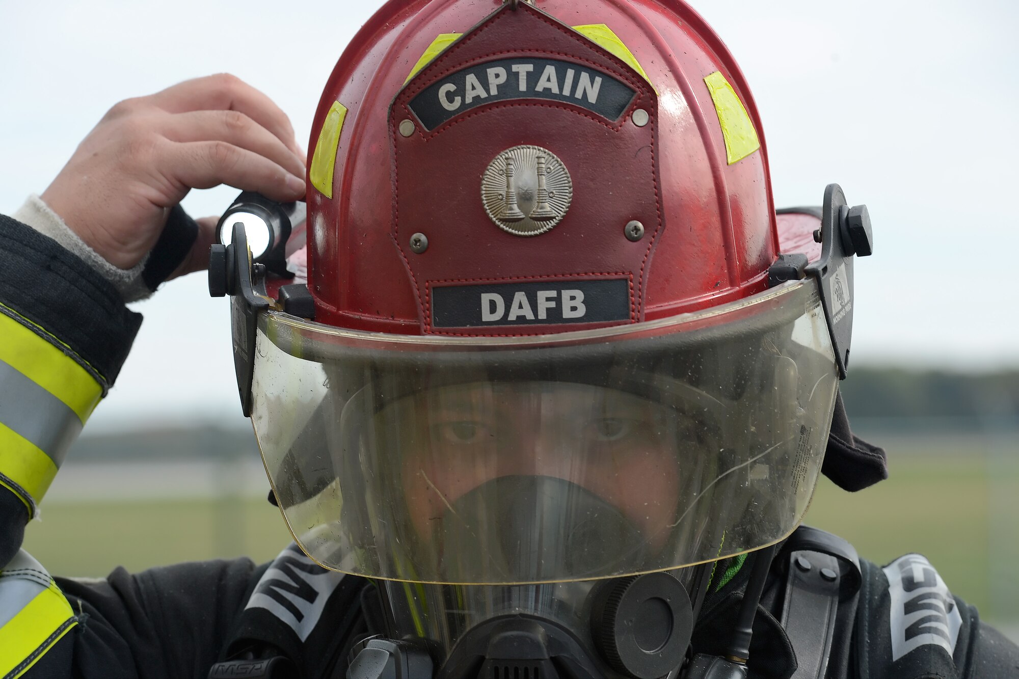 Tech. Sgt. Ryan Atoigue, 436th Civil Engineer Squadron firefighter, adjusts a light attached to his helmet while participating in structural fire training Oct. 20, 2014, at Dover Air Force Base, Del. Atoigue's helmet indicates that he is a firecrew captain at Dover Air force Base. (U.S. Air Force photo/Greg L. Davis)  