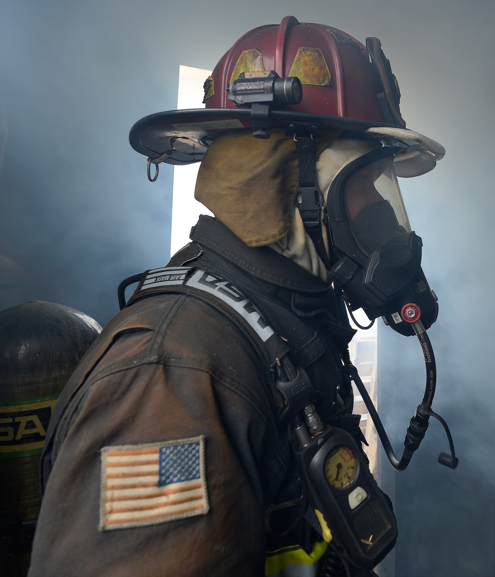 Aaron Weisenberger, 436th Civil Engineer Squadron firefighter, works in a smoke-filled room while protected by his firefighting clothing and equipment during a structural fire training event Oct. 20, 2014, at Dover Air Force Base, Del. Weisenberger's helmet shows visible results of extreme heat as the yellow reflective stickers melt in-place. (U.S. Air Force photo/Greg L. Davis)