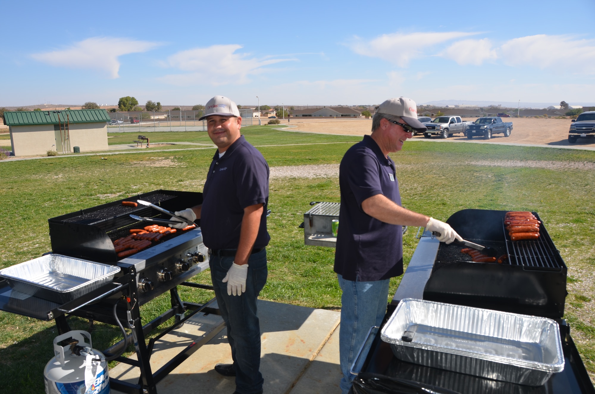 Corvias team members, Felipe Medina (left) and Richard Karow grill up hundreds of hotdogs for the 2014 Fallapalooza. More than 560 hotdogs and 400 caramel-covered apples were consumed during the event. (Courtesy phtoto by Mark Nettles)
