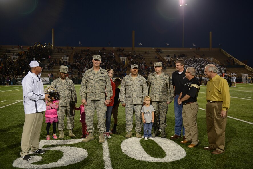 Steve Warren, left, Abilene High School (AHS) Eagles head football coach, presents 7th Bomb Wing and 317th Airlift Group leadership with a team helmet during the pre-game ceremony at the AHS football game Oct. 17, 2014, in Abilene, Texas. The Abilene Independent School District and AHS wanted to show their appreciation to the men and women of Team Dyess for their patriotism and devotion to the country. (U.S. Air Force photo by Airman 1st Class Kedesha Pennant/Released)
