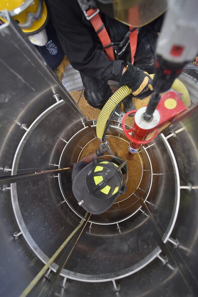 A firefighter from a local fire department simulates a victim trapped in a grain storage bin here, Oct. 17. Entrapped in grain up to her waste, the firefighter uses a grain vacuum to remove the grain around her after members of her team constructed a modular metal rescue cylinder to prevent grain from flowing back onto her. As the first product of the Air Force Community Partnership Program at YARS, the Ohio Bureau of Worker’s Compensation worked with the Ohio State Fire Academy to bring their innovative grain bin rescue training platform to YARS, allowing first responders to gain potentially life-saving skills. Approximately 50 firefighters from several local fire departments, including 14 from the 910th Civil Engineer Fire Department here, participated. U.S. Air Force courtesy photo.